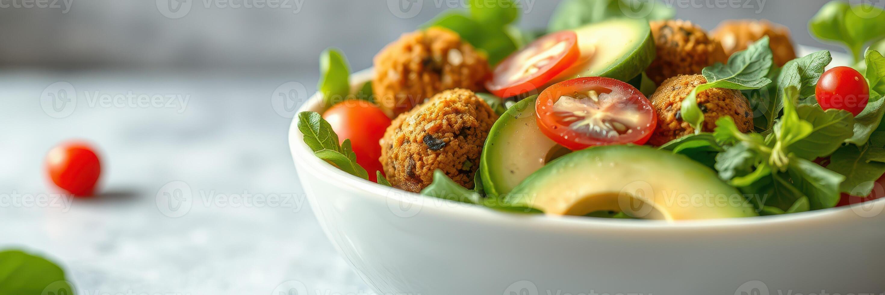 Fresh vegetable salad with falafel balls garnished with cherry tomatoes and cucumber slices photo