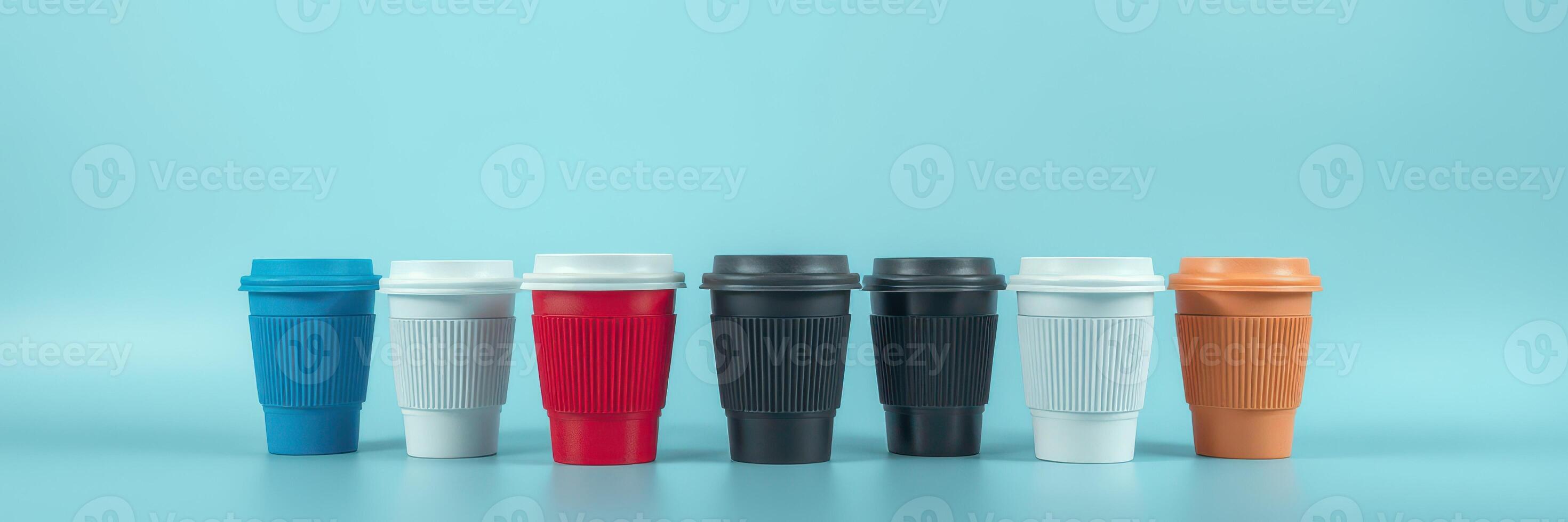 Various disposable coffee cups in different colors and sizes arranged on a blue background in an artistic display photo