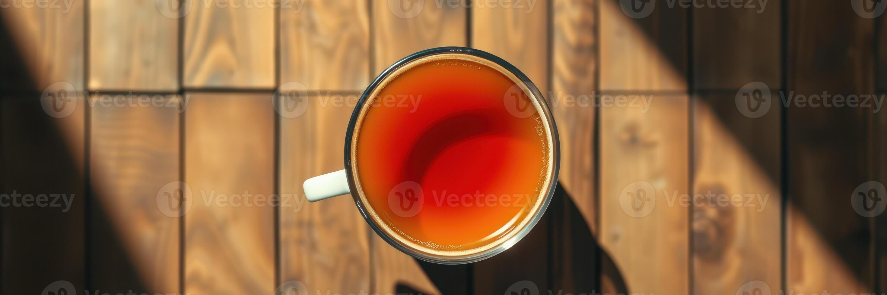 Warm cup of tea resting on wooden table in afternoon light showcasing rich color and tranquil atmosphere photo
