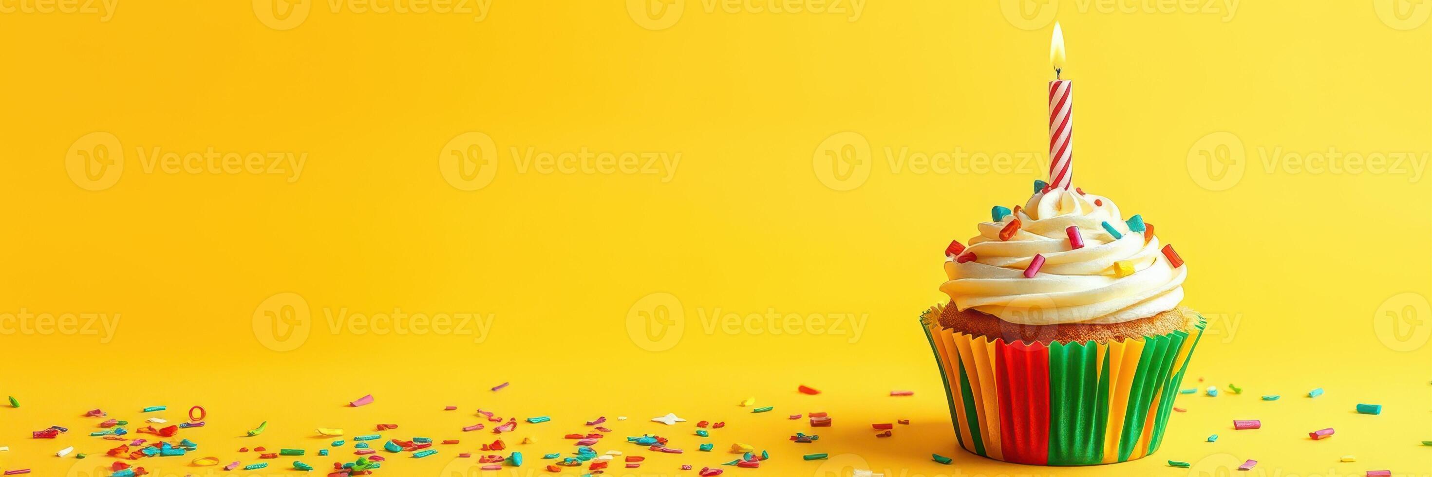 Colorful cupcake with a candle and sprinkles on a bright yellow background during a birthday celebration photo