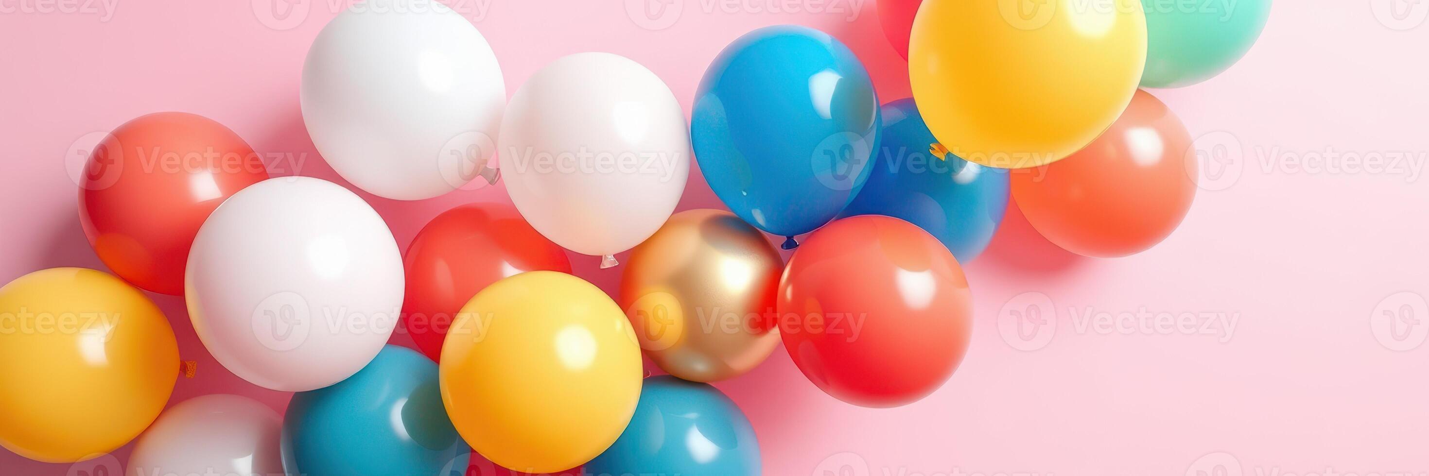 Colorful balloons of various shapes arranged on a pastel pink surface for a festive celebration photo