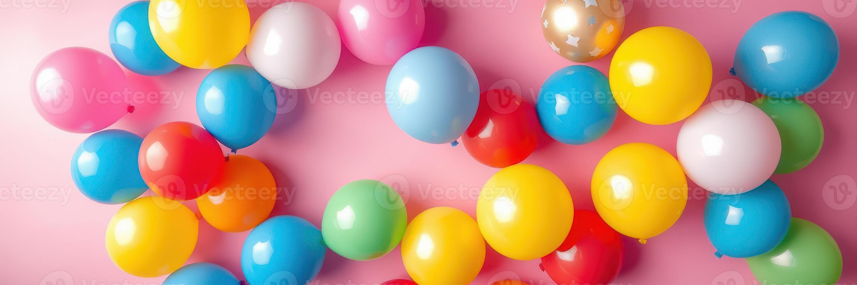 Colorful balloons scattered on a pink background create a festive atmosphere for celebrations and parties photo