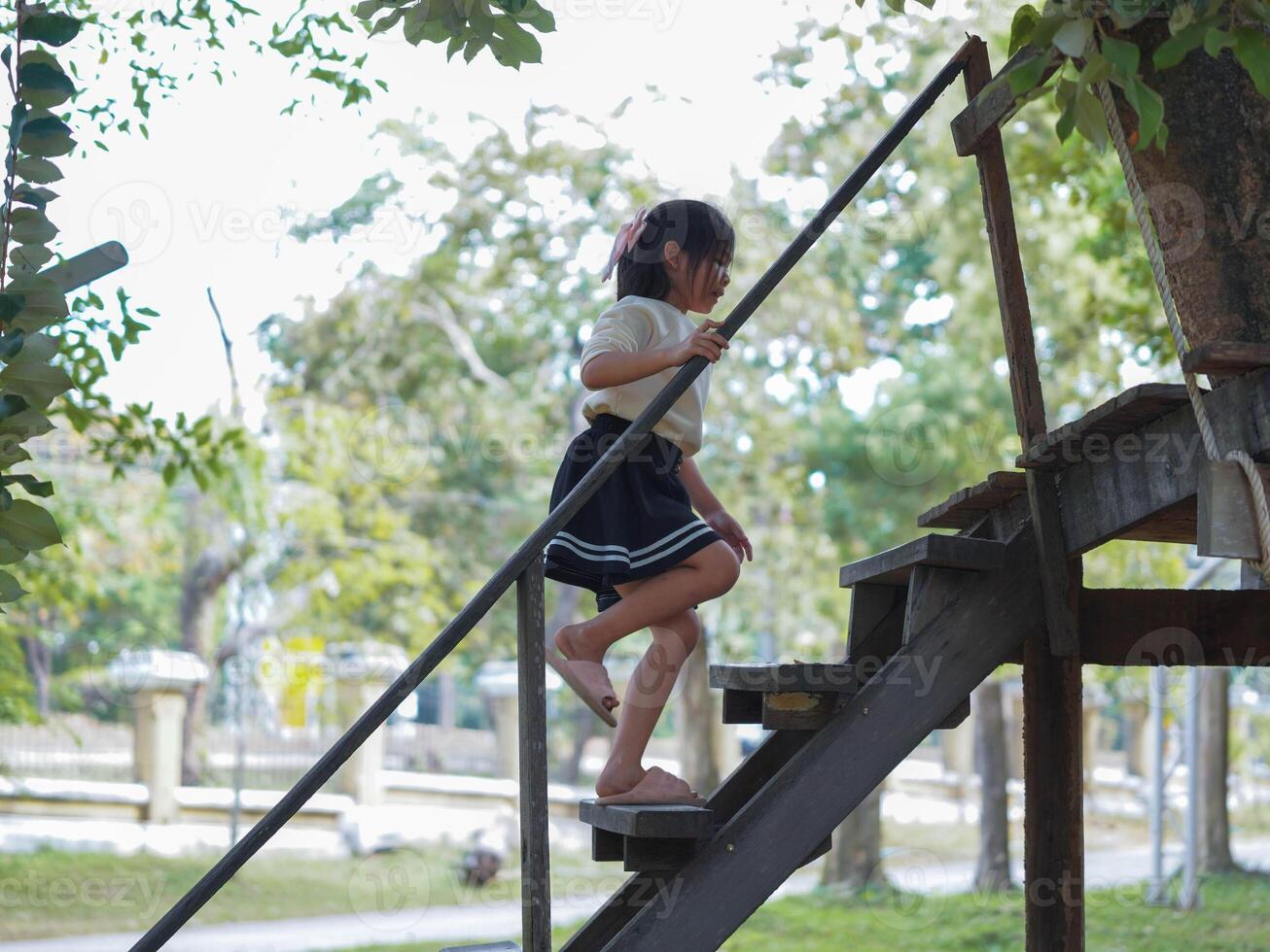 A cute girl is walking up a wooden staircase in a park. photo