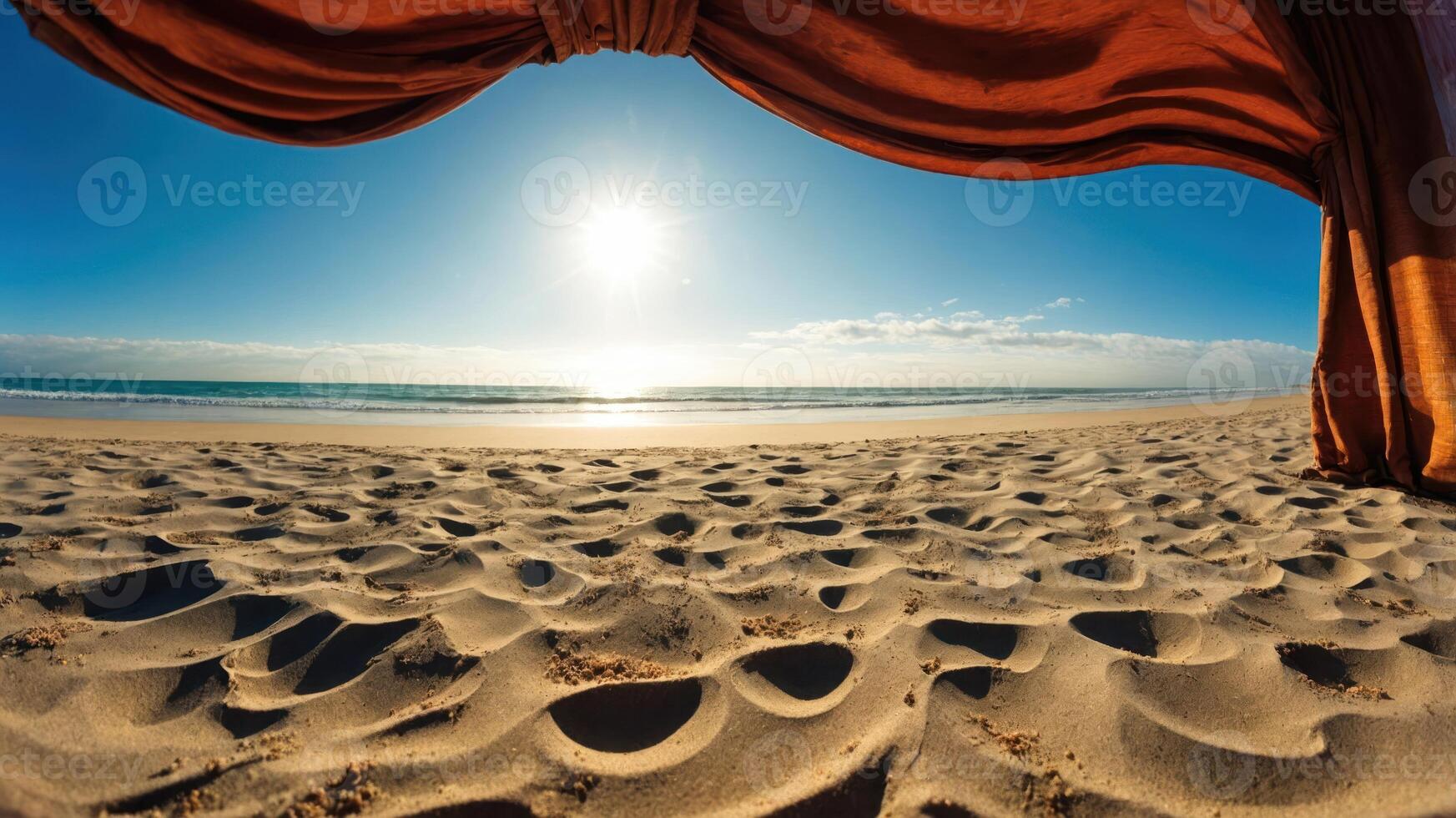 A serene beach view framed by draped fabric, highlighting the sun and tranquil waves. photo