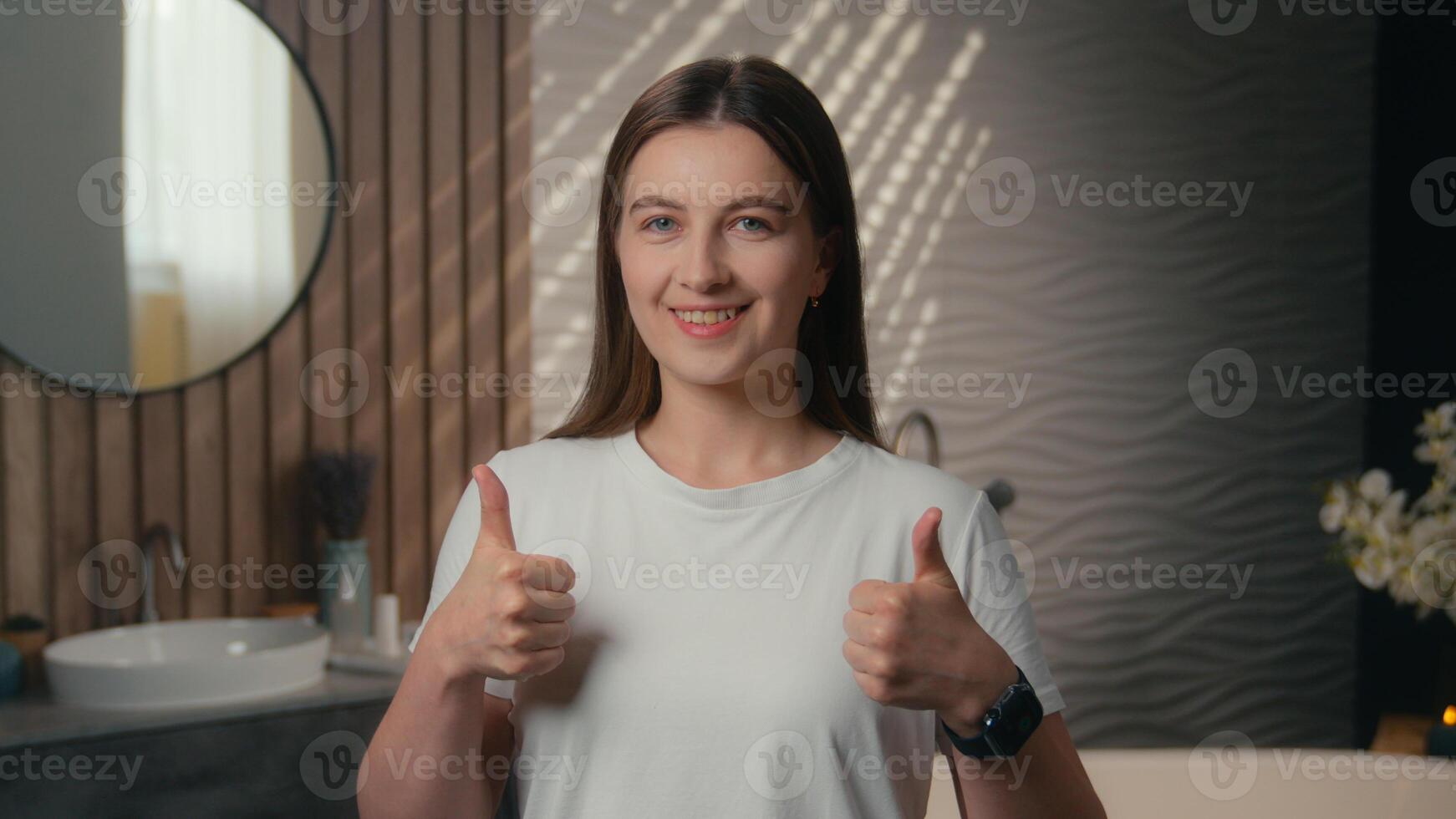 Caucasian smiling girl healthy woman beautiful female in bathroom hotel happy lady thumbs up gesture raise finger good recommend hotel bath spa beauty procedure face skin cosmetics skincare product photo
