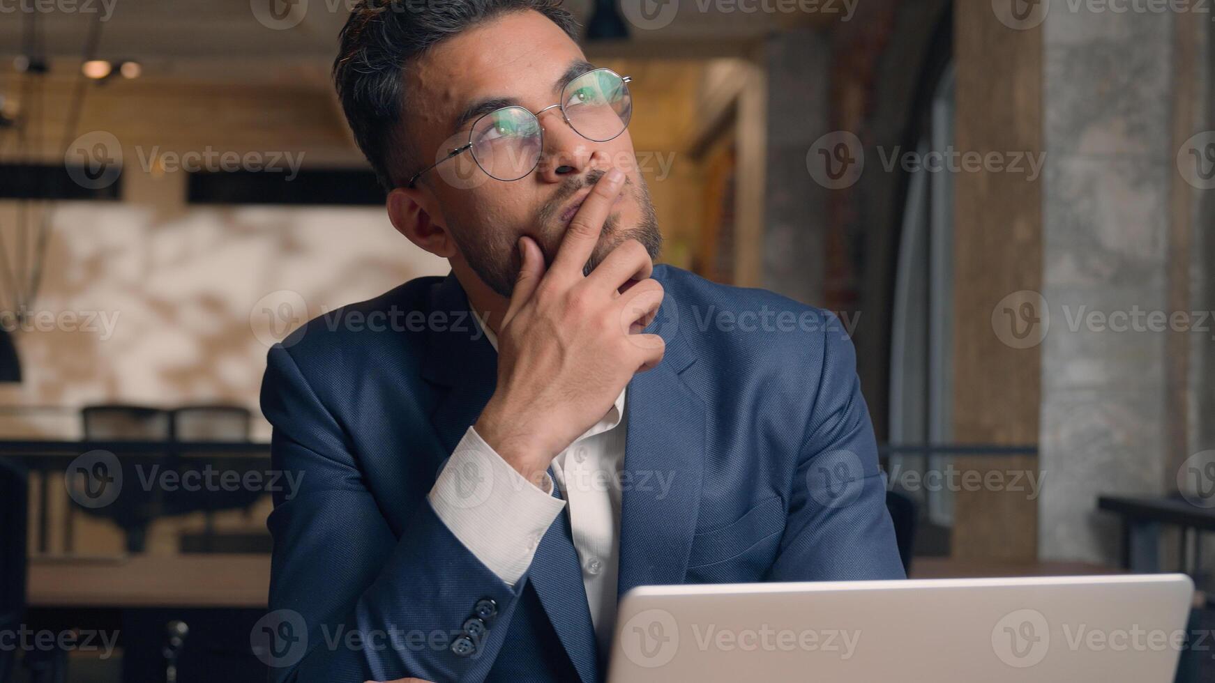 Thoughtful puzzled businessman Arabian Indian man thinking male guy employer worker think idea business plan strategy ponder consider doubt choose remember decide search deep thought question indoors photo