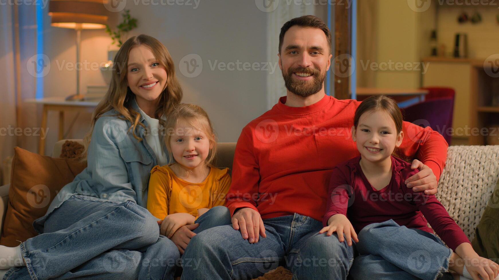 Happy family Caucasian mother father cheerful mom dad love children kids little girls daughters on sofa couch relax together bonding cuddling evening weekend holiday at home loan mortgage relocation photo