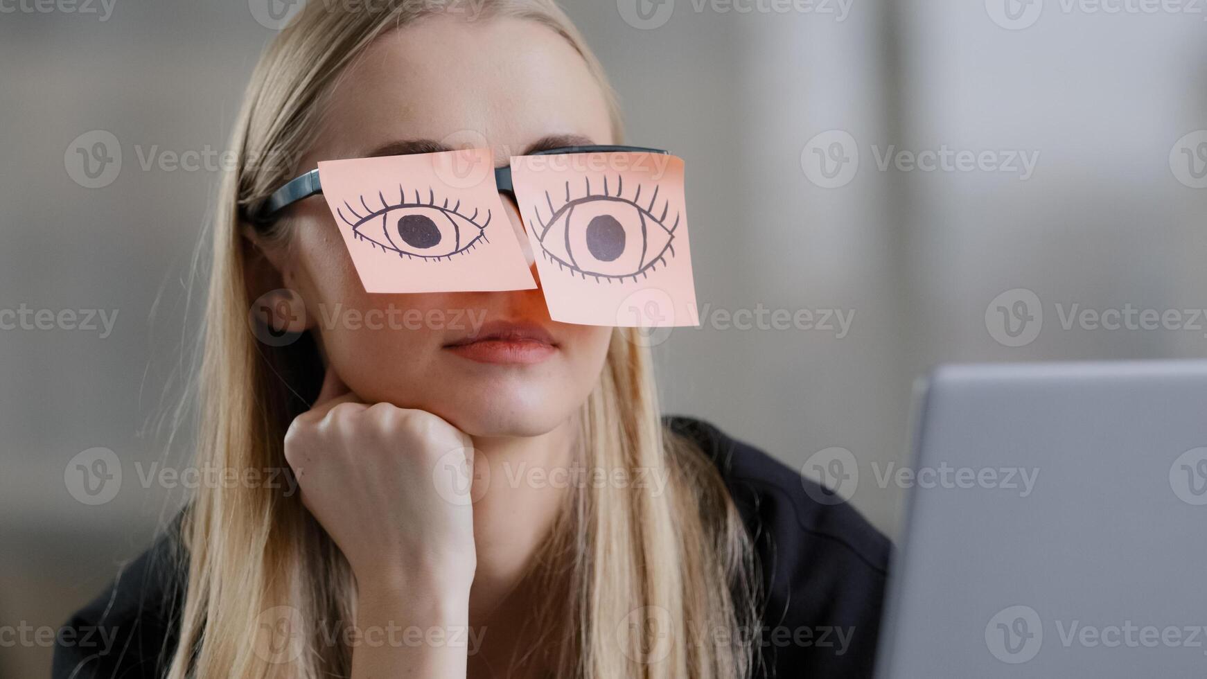 Tired female unmotivated manager with stickers on eyes sitting at desk sleeping at workplace chronic fatigue lazy businesswoman in office exhausted napping relaxing with sticky notes on eyeglasses photo