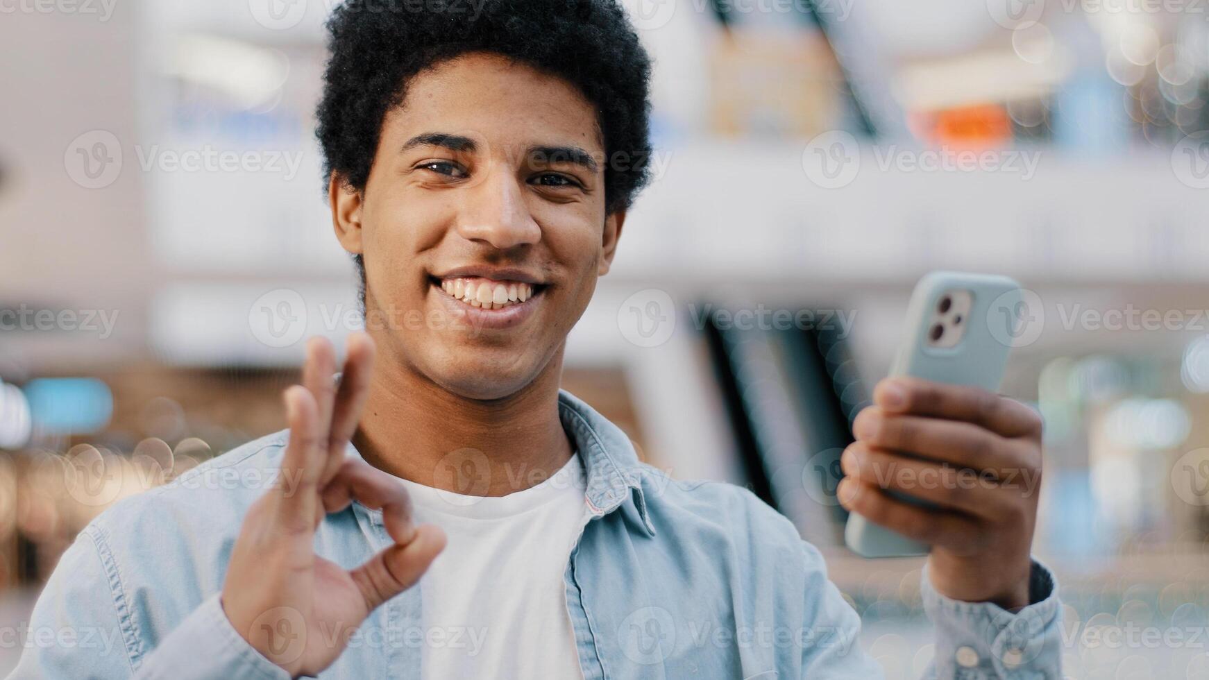 African american guy satisfied happy positive man with mobile phone showing ok sign okay gesture success winning good recommendation smartphone online app network telephone wi-fi chat using device photo