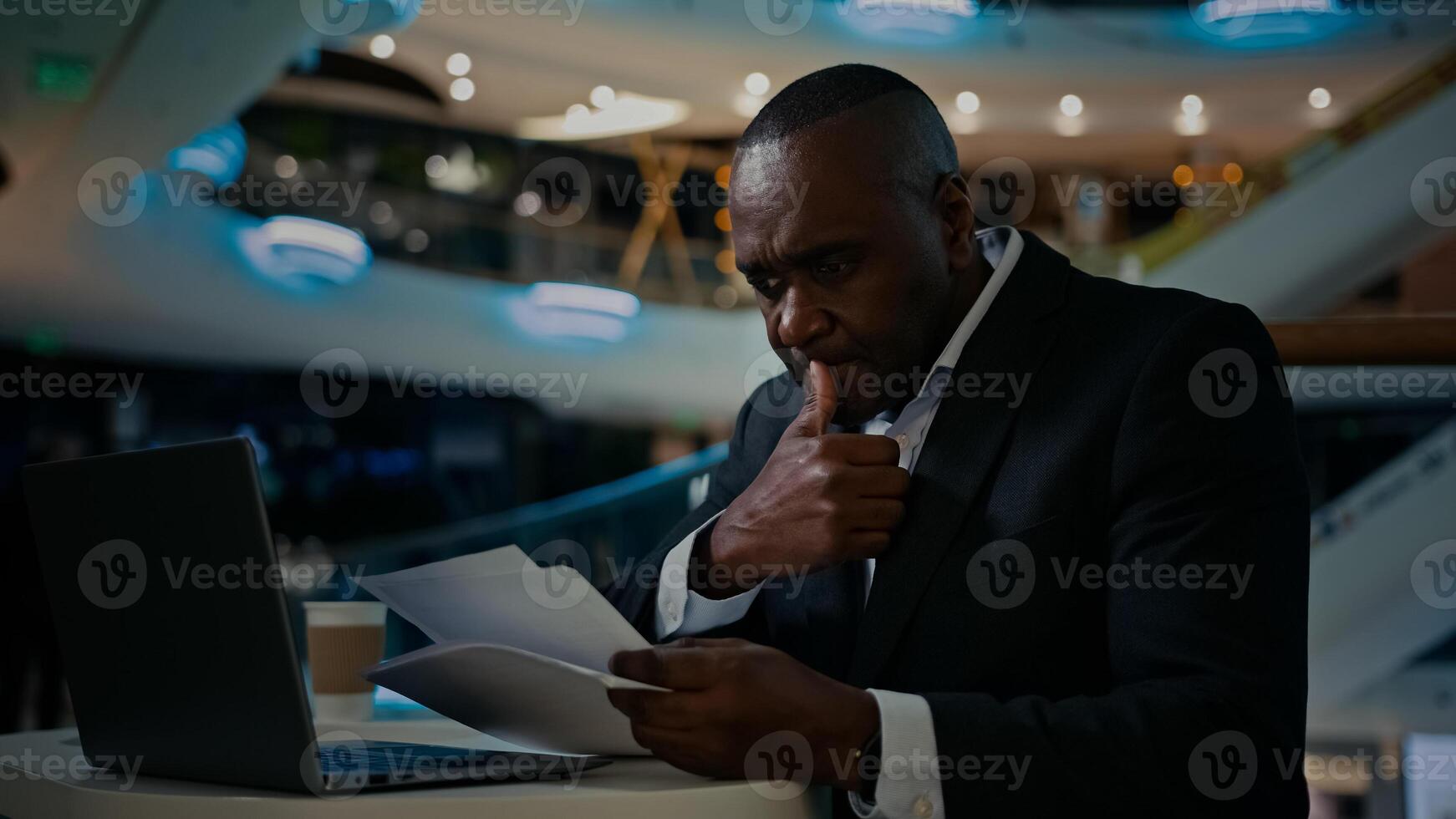 Middle-aged adult pensive thinking thoughtful man African entrepreneur businessman check papers working with documents worker inspect paperwork project think pondering work with laptop accounting photo