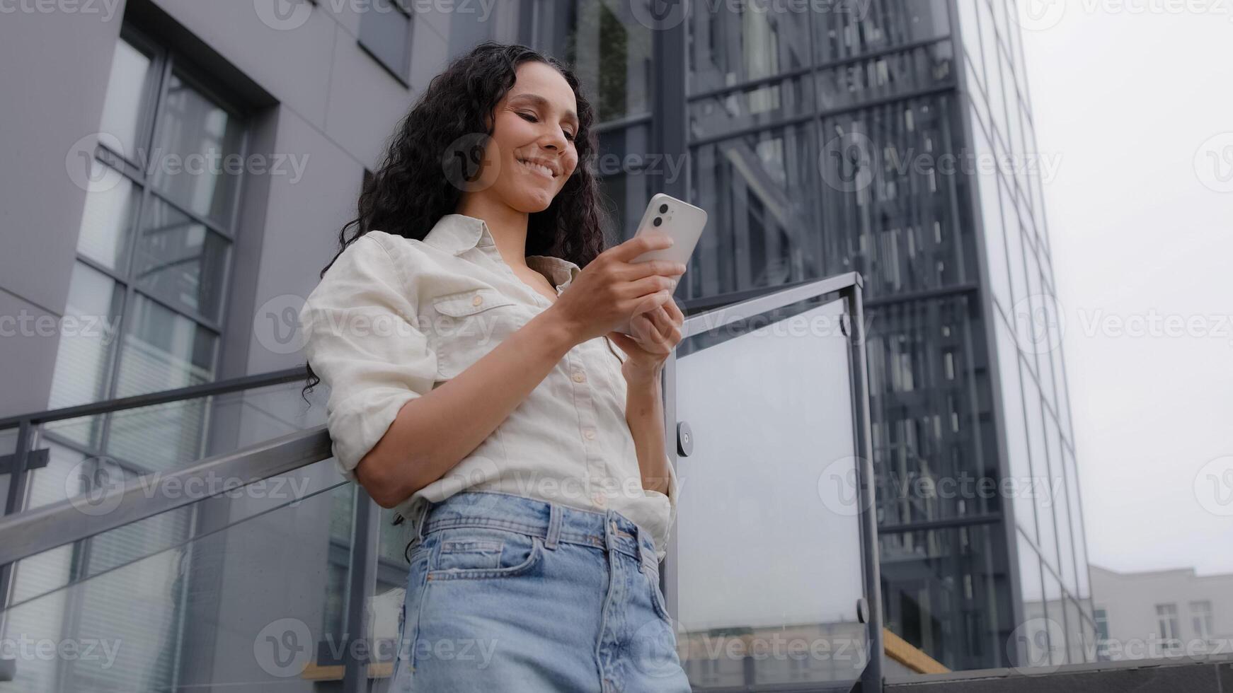 Bottom view Caucasian Hispanic 30s woman in city female tourist businesswoman with phone outdoor typing in smartphone chatting text message browsing online watching map app mobile service booking taxi photo