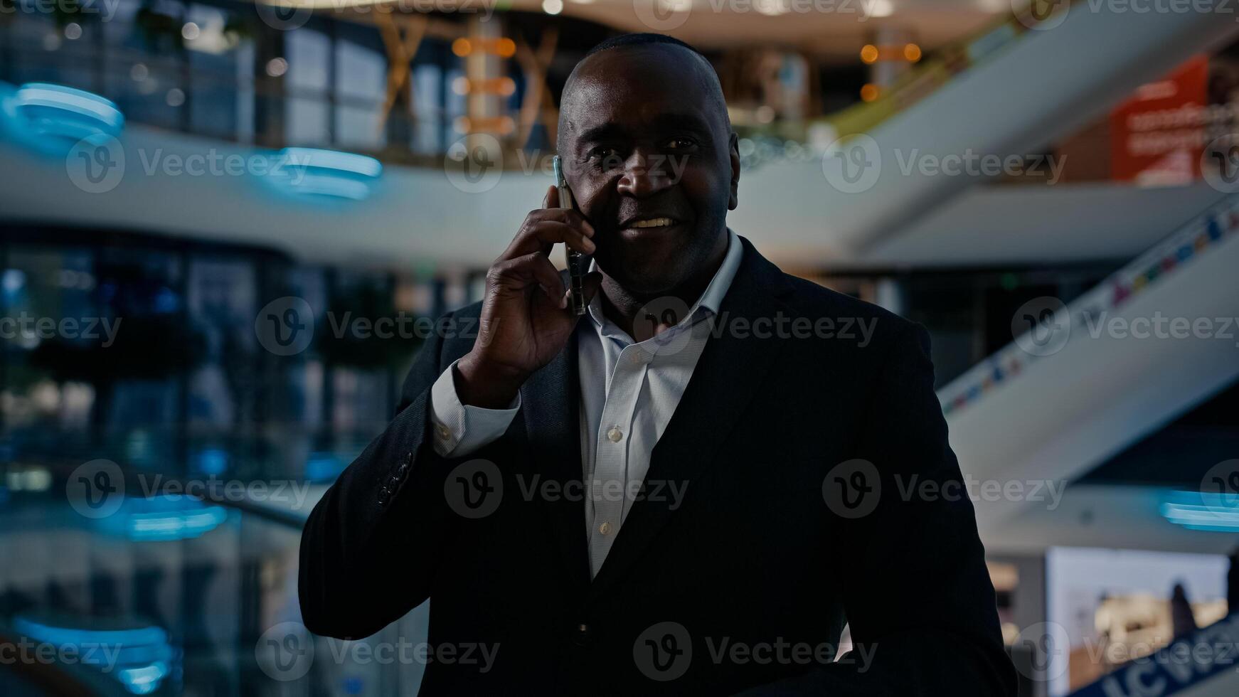 Adult businessman African American middle-aged man employee entrepreneur indoors in office mall company talking phone chatting mobile conversation talk speak business negotiation with smartphone call photo