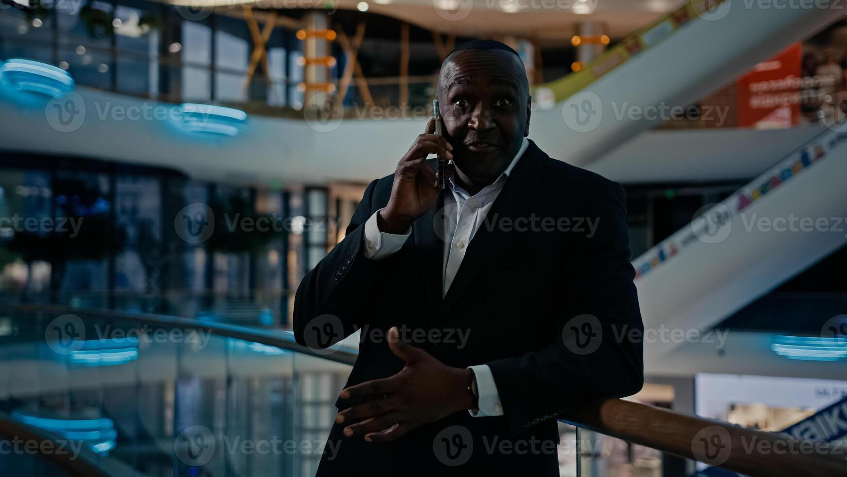 50s advisor man phone call colleagues business partner talking with smartphone indoors in office company pointing direction explaining. African entrepreneur businessman calling answer talk cellphone photo
