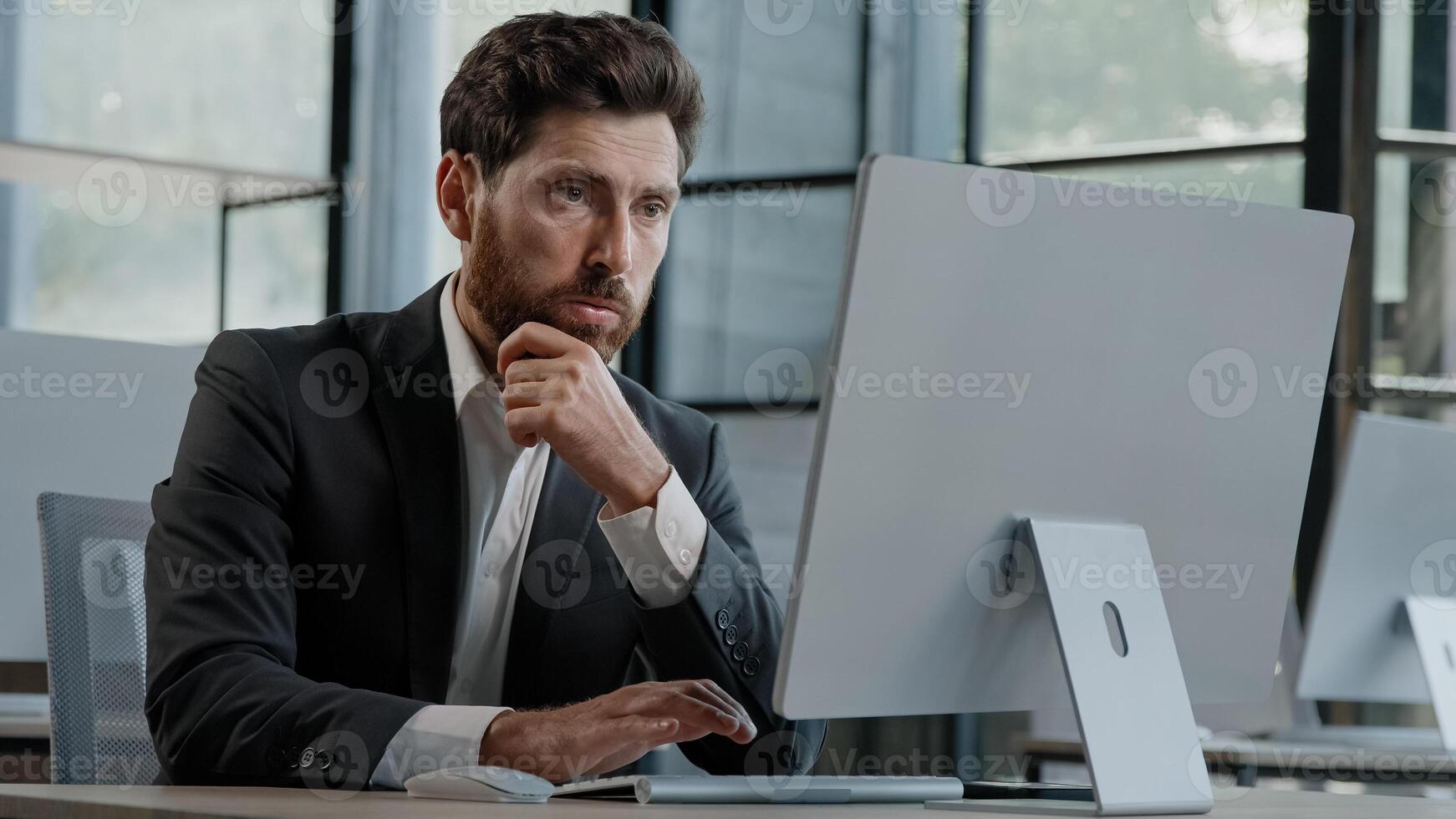 Focused Caucasian bearded adult 40s man CEO company worker manager boss businessman working on computer in office searching solution of problem decide difficult task creating online project thinking photo