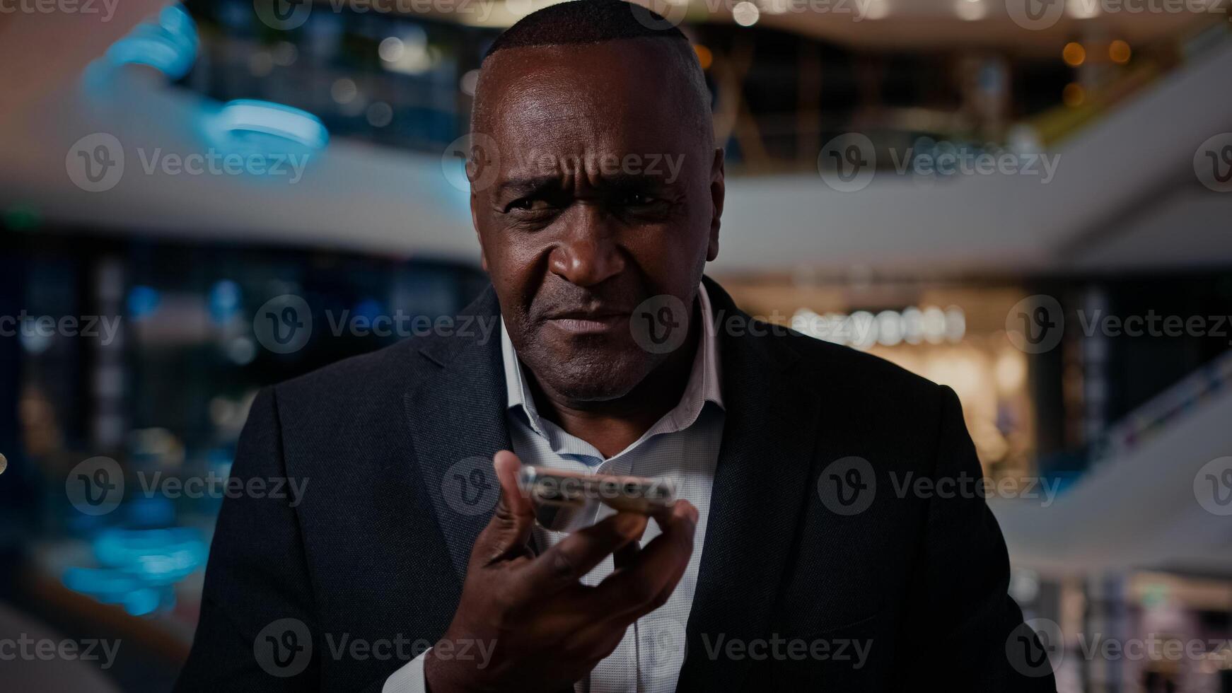 Middle-aged 50s man entrepreneur talking mobile phone call business negotiation record voice message answer audio email talk with smartphone loudspeaker businessman indoor with cell using easy command photo