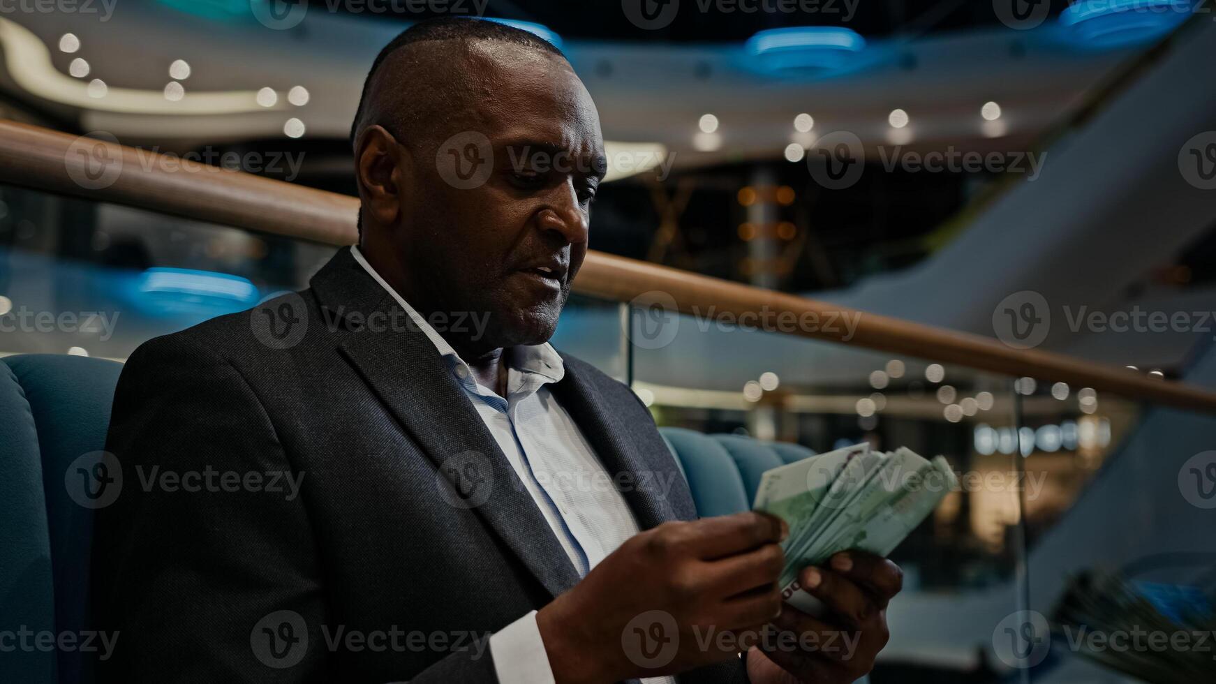 Close up rich 50s African businessman calculate dollars euro indoors. Middle-aged American man CEO entrepreneur mature male accounting finances employer account money bills broker calculating cash photo