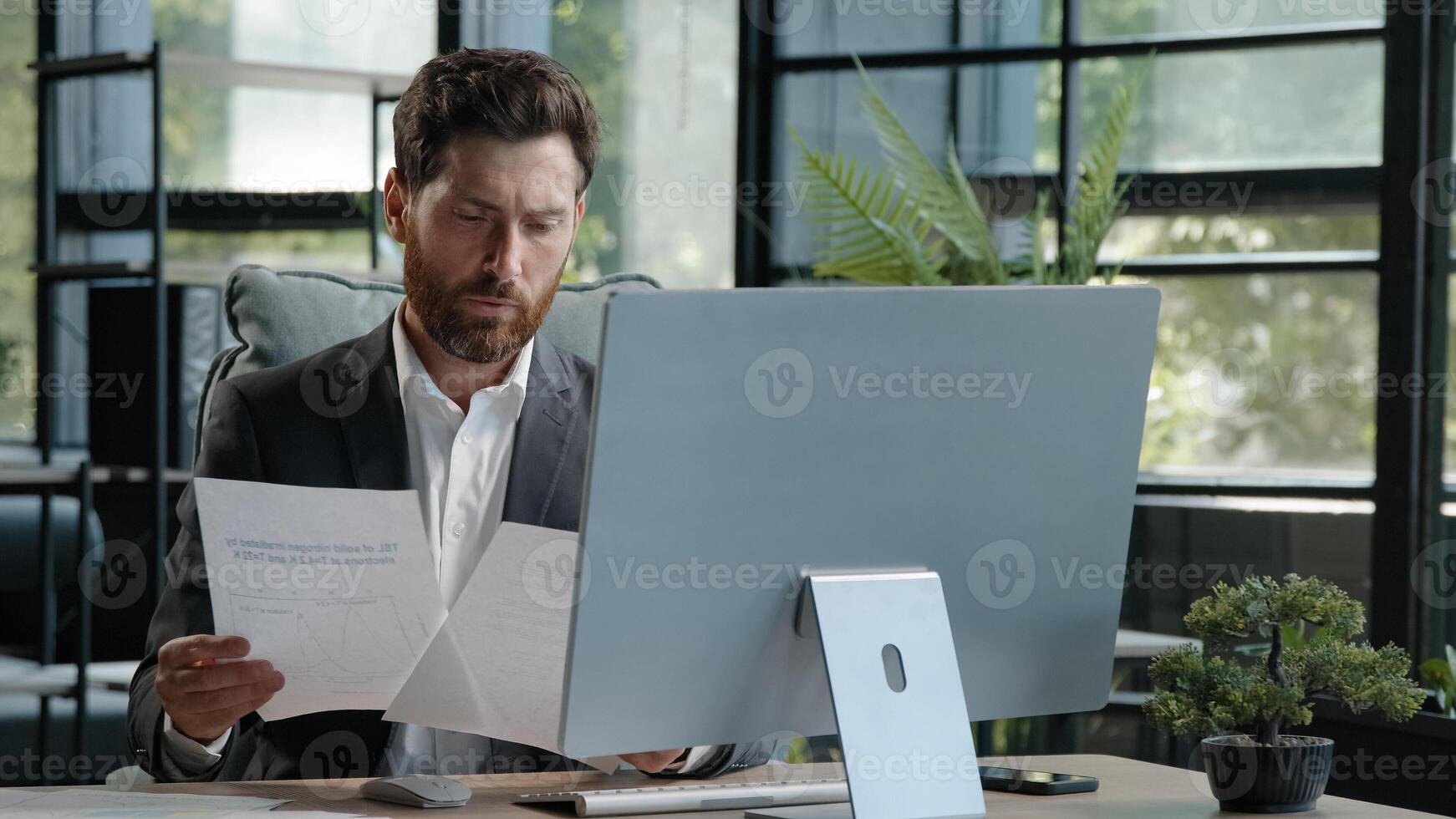 Busy Caucasian pensive man boss manager adult 40s businessman sitting in office work with paperwork and computer check data in papers search information look at screen corporate company app project photo
