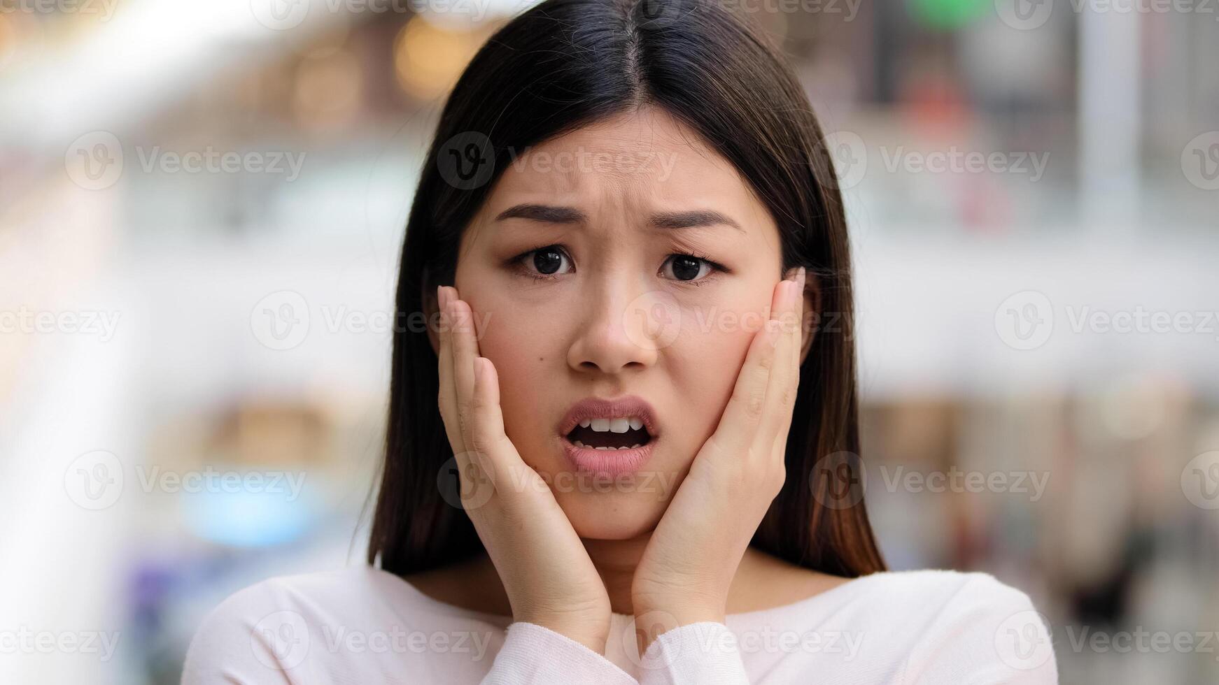 Headshot female emotional face asian ethnic korean girl 20s woman model frightened lady scared fear horror disgust holding hands behind head from shock afraid turning away unpleasant bad news concept photo
