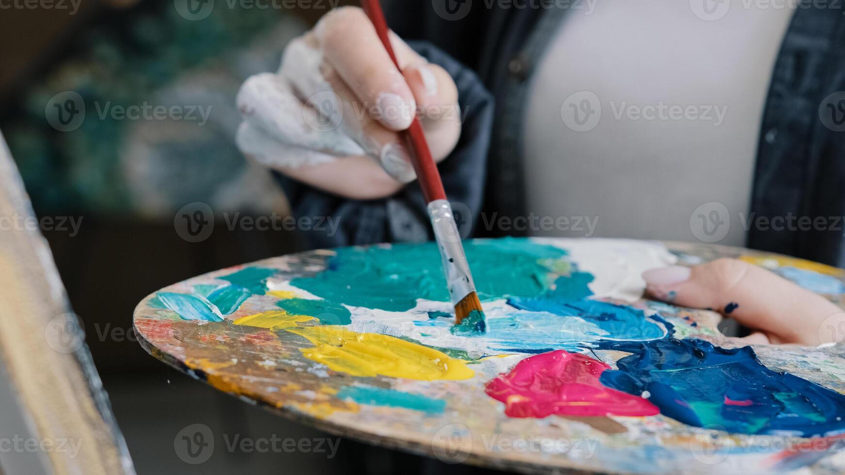 Closeup woman female hand artist painter paints draws creating new art work on canvas in workshop lesson of painting enjoying process of drawing creating picture using brush applying oil paint palette photo