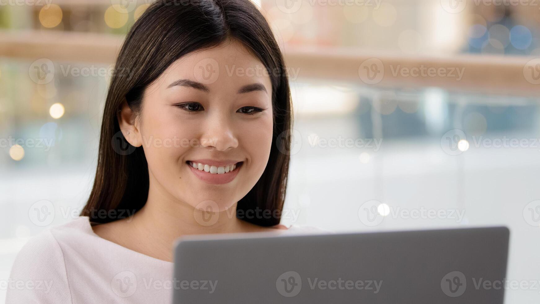 Portrait smiling happy asian female face looking at laptop satisfied girl woman freelancer boss worker manager typing computer using shopping app service watching online on website browsing net photo