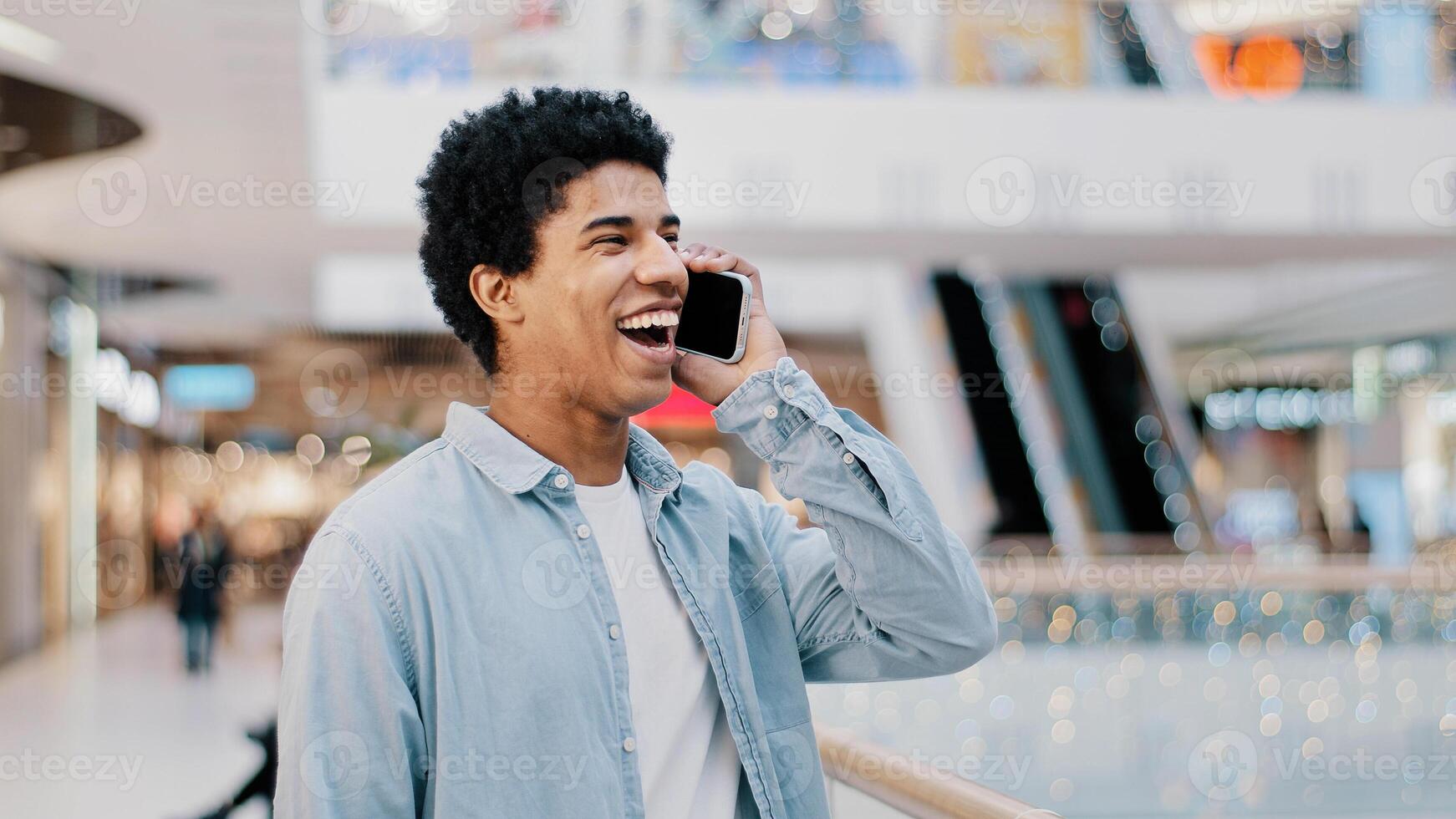 African friendly African man with smartphone indoors happy smile talking conversation casual chatting with friends smiling answer call. Biracial guy has nice talk with mobile phone remote negotiation photo