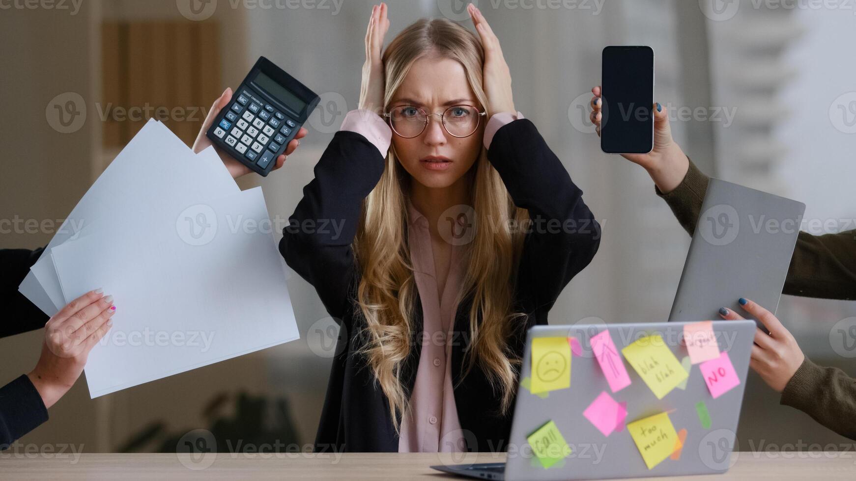 Sad overworked exhausted tired business girl with woman worker manager in glasses holding head multitasking stress problems with work sitting table with laptop around calculator notebook papers phone photo
