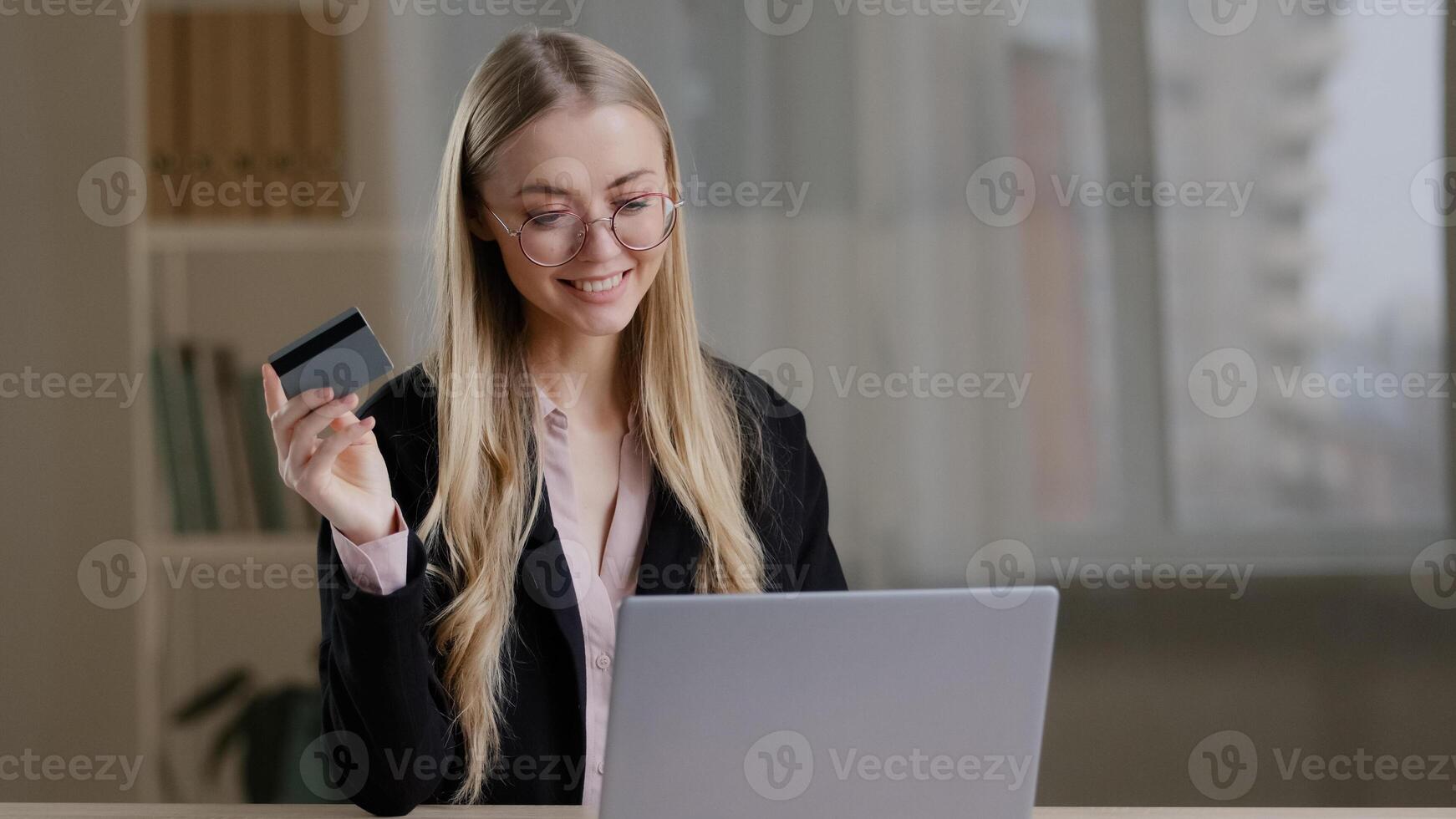 Rich caucasian business woman shopping online using laptop paying with credit bank card buy order booking remotely net. Happy 30s female with glasses purchas website internet banking secure system photo