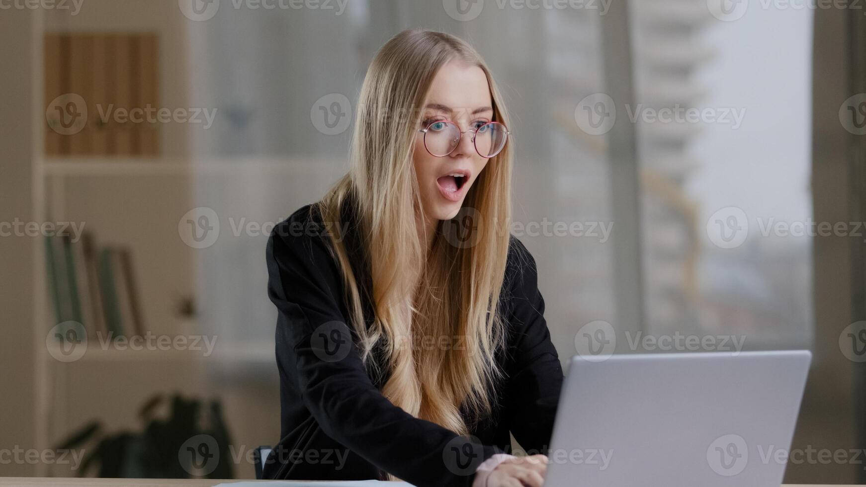 Successful caucasian millennial business woman girl in glasses wins in online betting receives notification with good news positive results offer victory shouts happiness rejoices hands up success photo