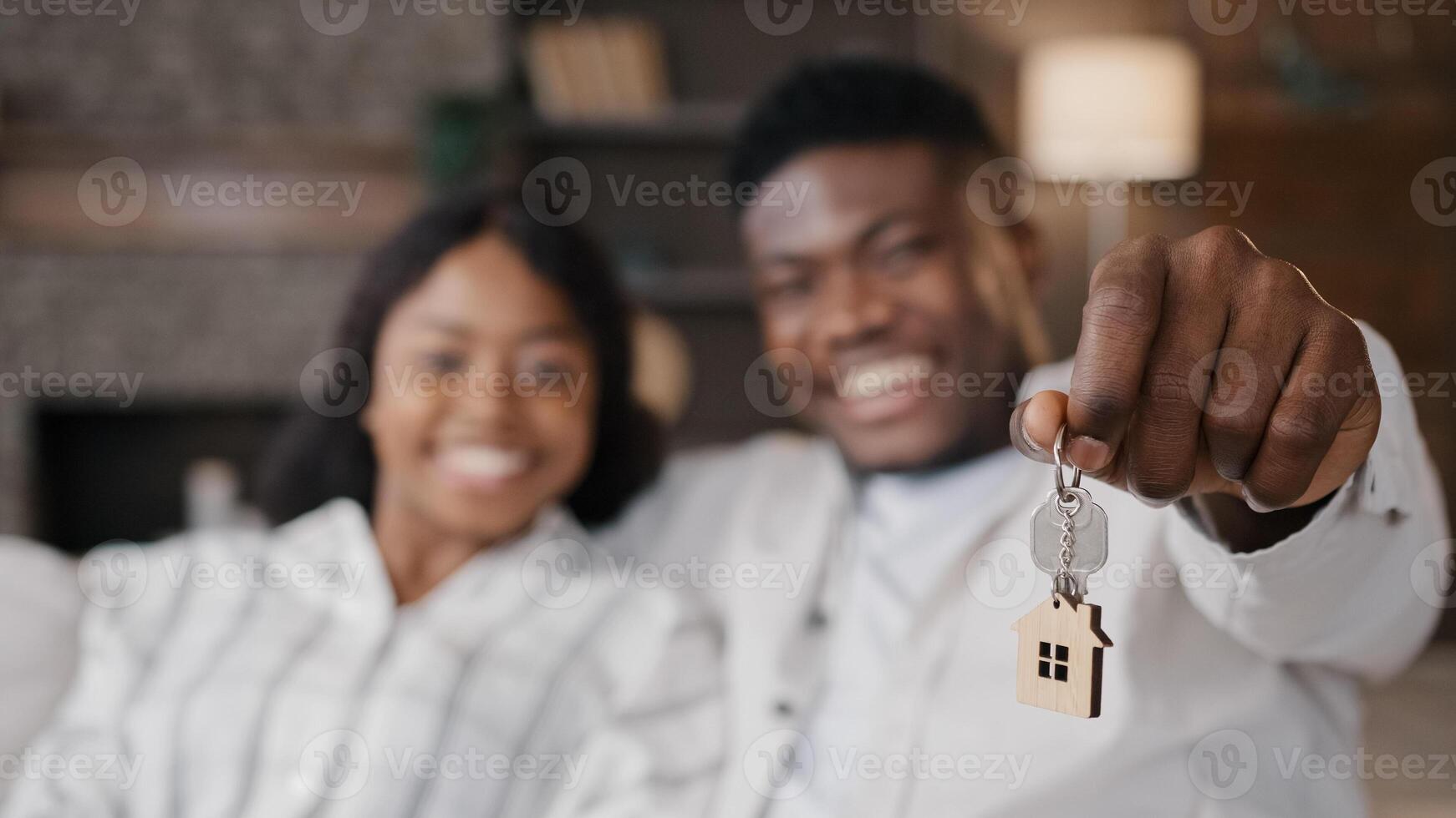 Blurred unfocused view African American married couple newlyweds wife and husband holding keys to new house rented apartment happy with real estate. Girlfriend and boyfriend satisfied living together photo