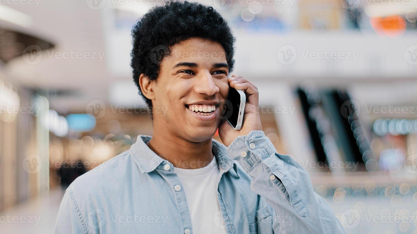Close-up african guy looking at mobile phone answering unexpected call talking to girlfriend family smiling laughing chatting on cellphone remote friendly talk cellular connection using smartphone app photo