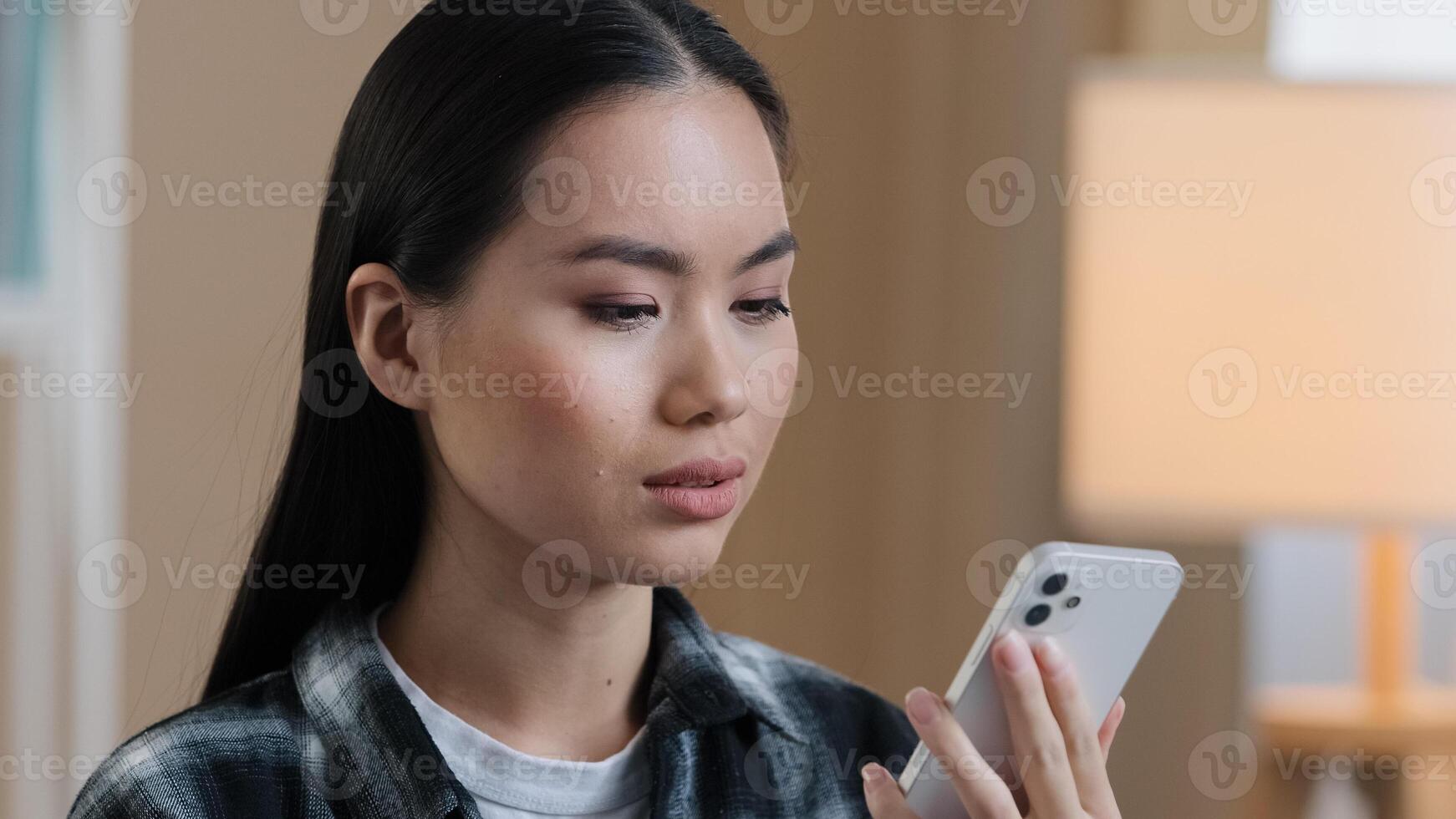 Portrait asian woman millennial confused angry girl indoors talking on phone answering call worries about bad mobile connection network problems cellular trouble broken smartphone breaking telephone photo