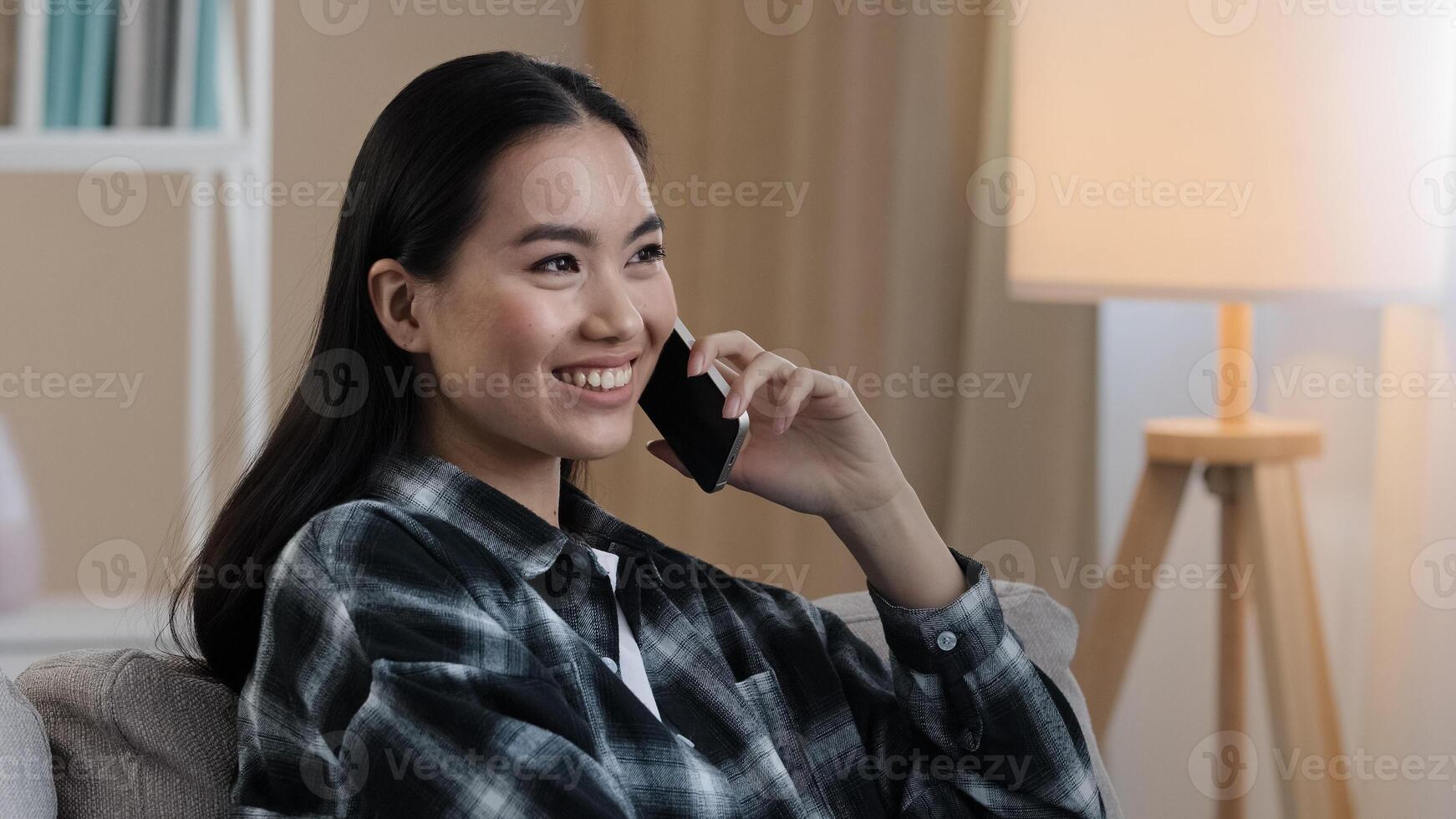 Asian korean japanese chinese girl millennial woman friendly remote talking with mobile phone cellular chatting talking with friend boyfriend family talking at home close up female face answering call photo