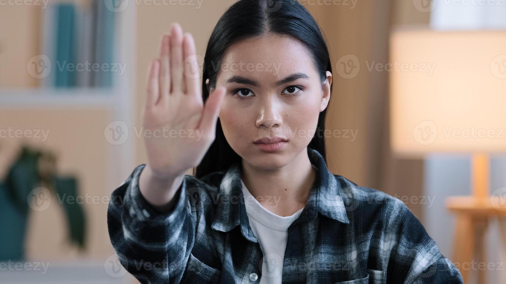 Portrait serious frustrated angry girl korean japanese chinese woman looking at camera holding hand in front forbidden gesture refusal keep distance stop gesture no sign refuse prohibits limitation photo
