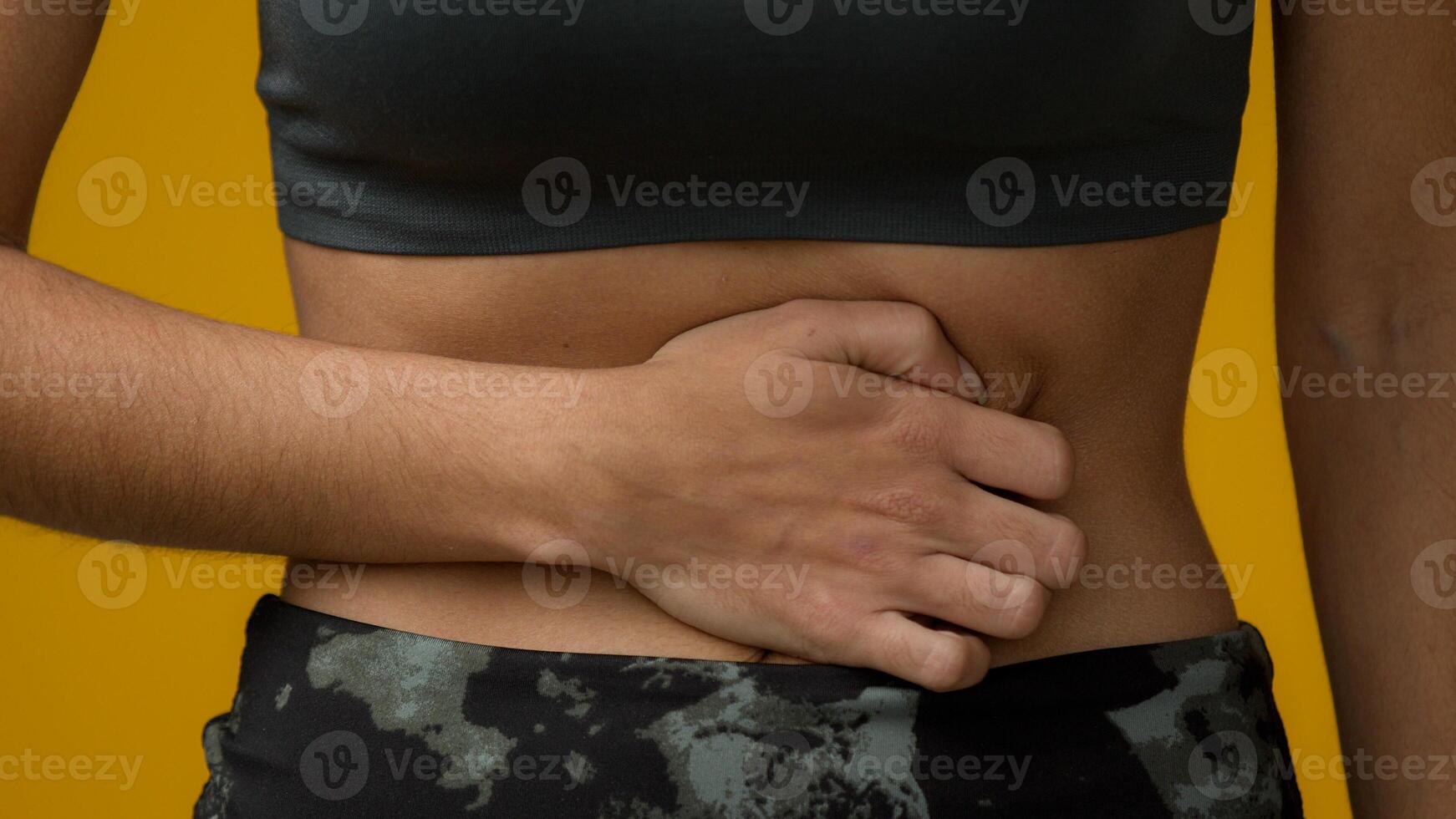 Cropped view unrecognizable girl female abdomen pain unknown woman holding belly suffer with ache bad discomfort painful abdominal constipation stomach sick menstruation in yellow studio background photo