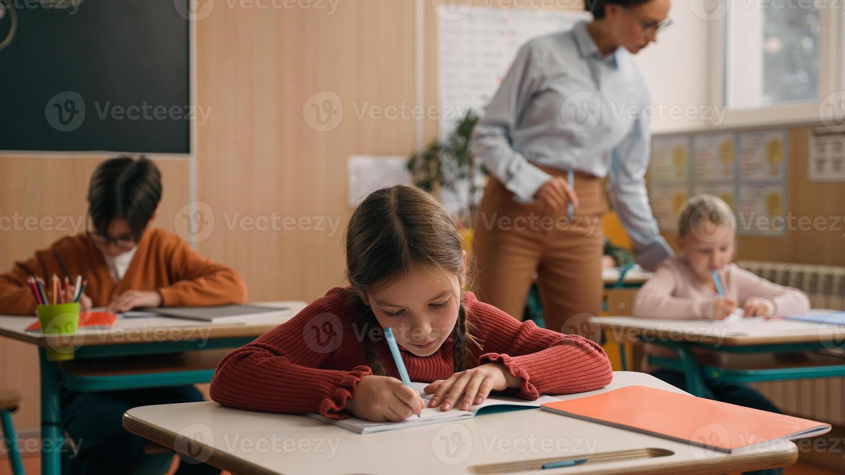School class lesson children studying learning in classroom woman teacher female tutor walking teaching little boy child kid rise hand ask help question answer study learn write talking education photo