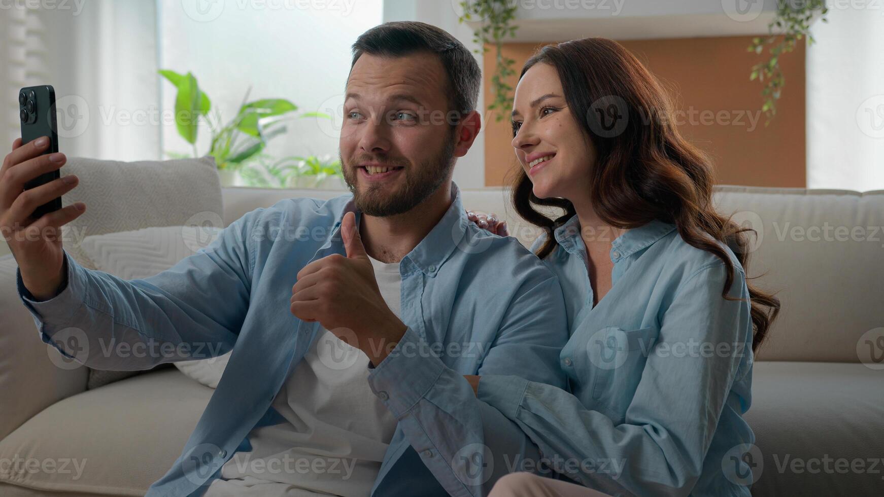Caucasian happy couple family waving hello showing thumb up talking conversation virtual call mobile phone conference chat blog vlog in social media bloggers speak at home with smartphone app photo