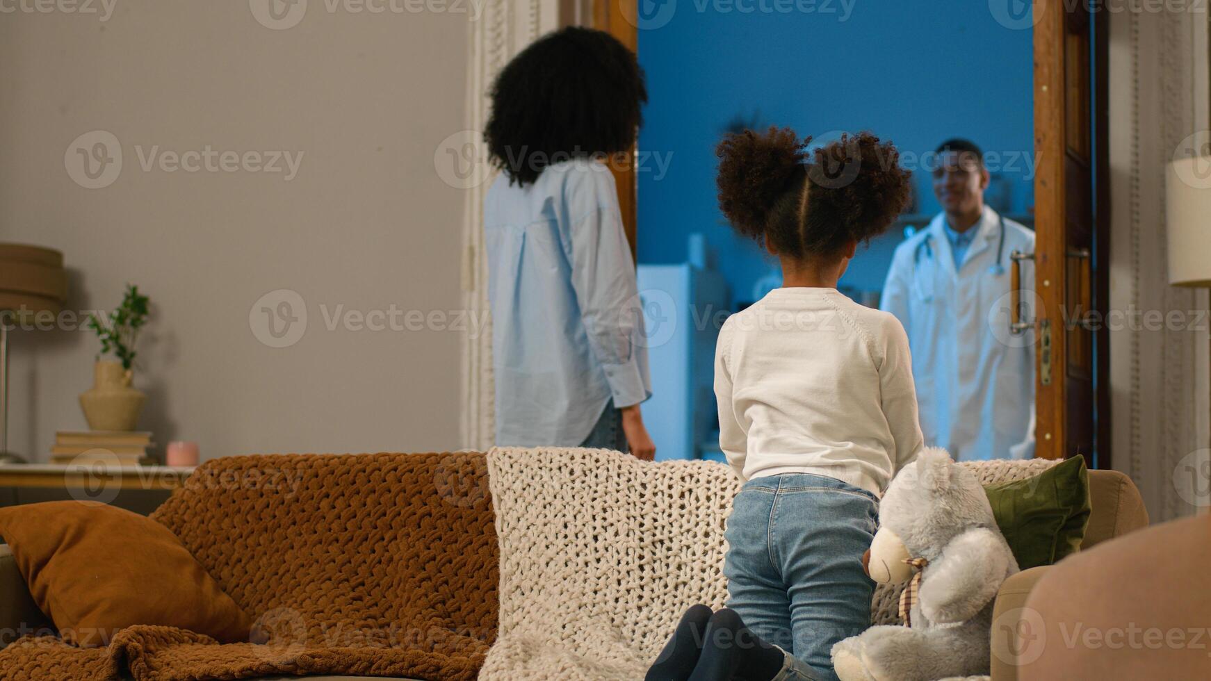 Mother daughter waiting doctor home visiting arrival therapist child little girl hugging toy teddy bear man woman talking health medicine worker help professional paramedic kid medicare sick illness photo