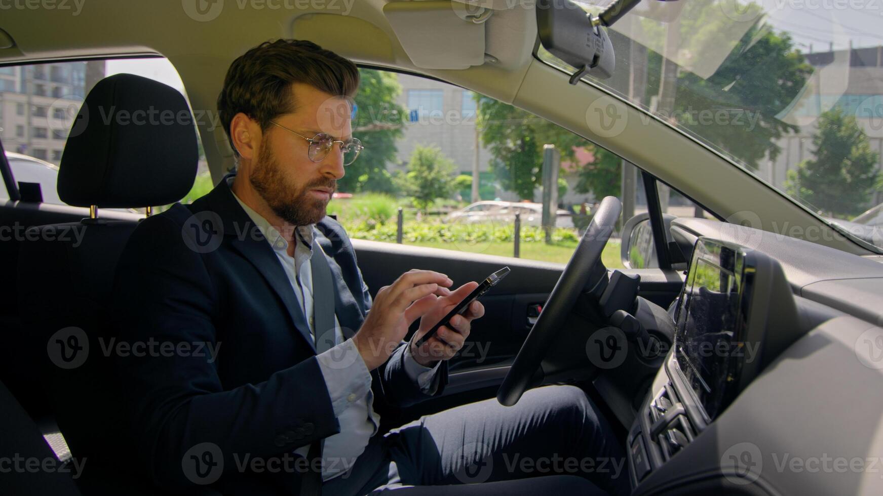 Business man inside modern electric car travel driving automobile in city displeased confused driver road destination auto navigation error worried using gadgets mobile phone gps app drive traffic jam photo