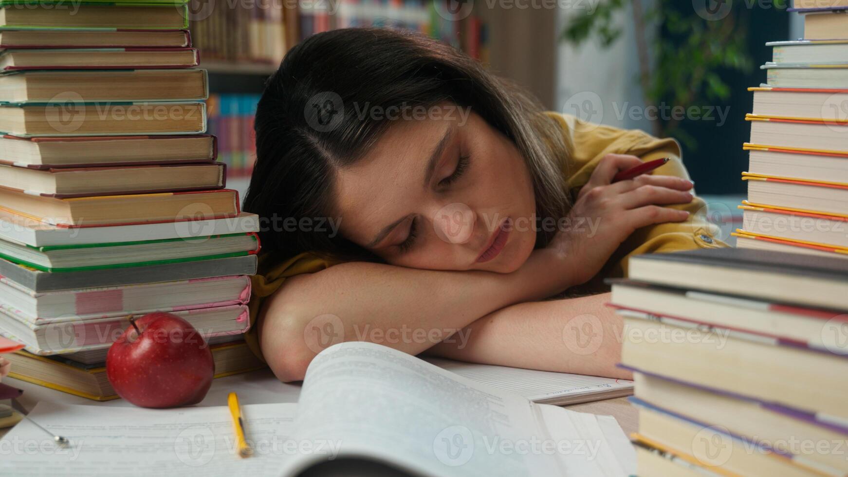Sleeping napping woman girl tired exhausted female high school student sleep on table desk pile books overwork prepare exam boring education study in university college academy library fall asleep nap photo