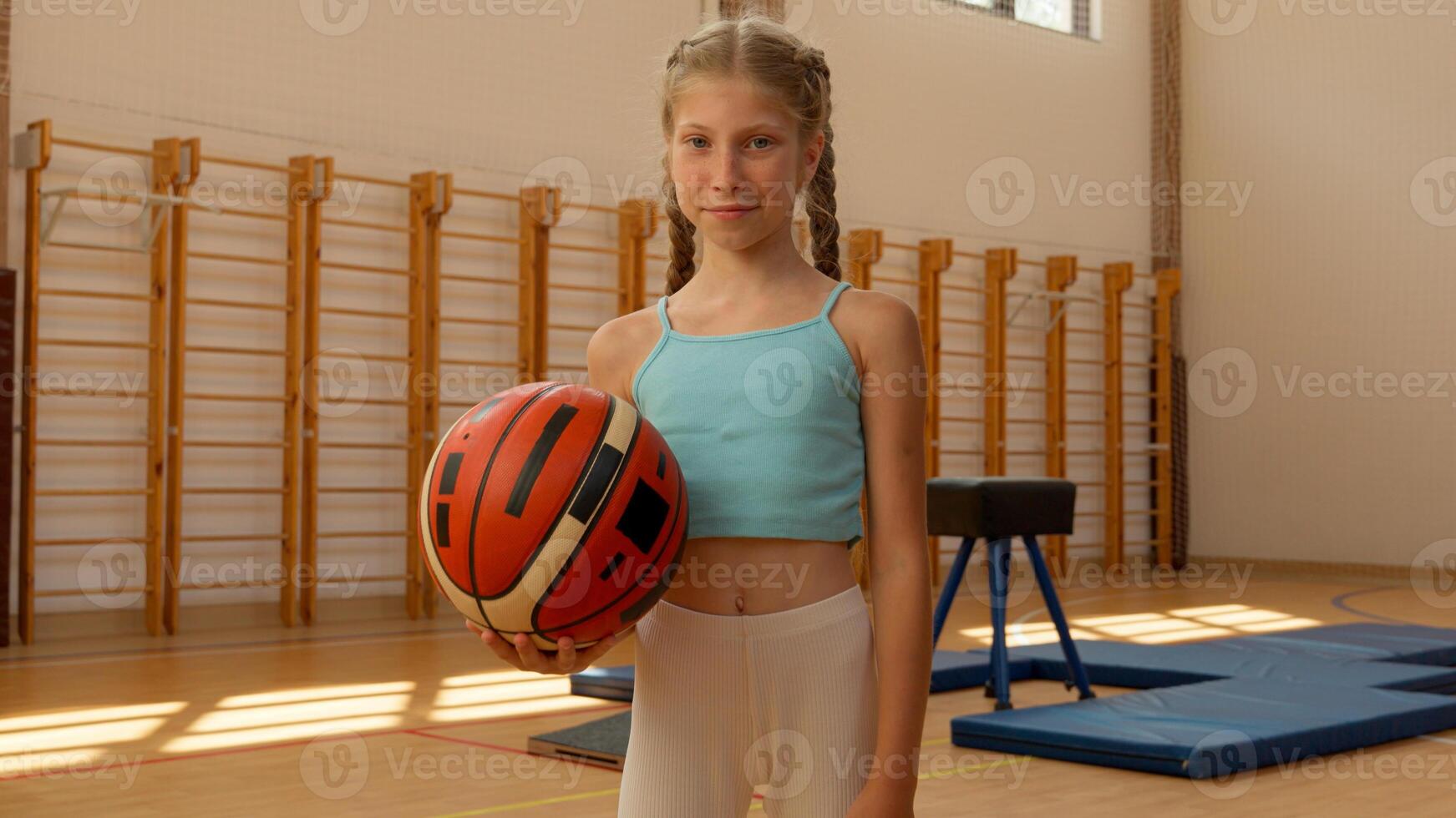 Young Caucasian girl little kid child daughter pupil schoolgirl student gymnasium class sport lesson in school playing basketball game throw ball female champion winner happy smiling education workout photo