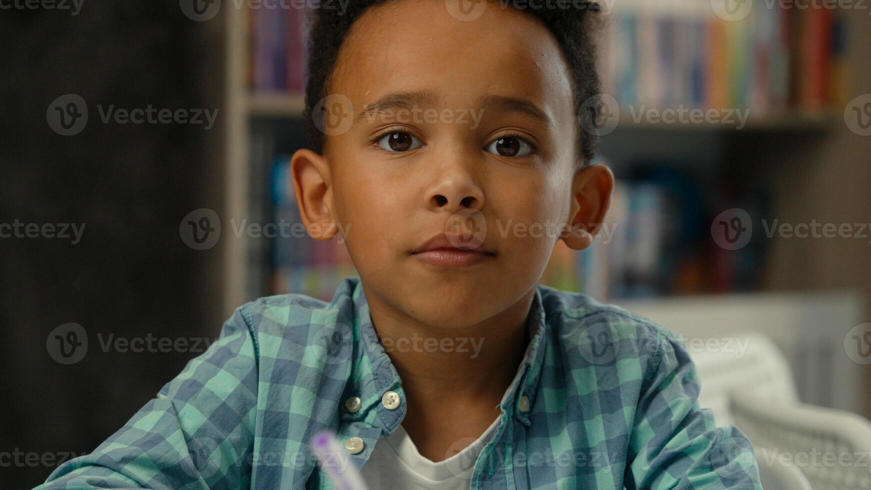 Little boy kid son African American ethnic child concentrated study learn write homework classroom lesson prepare task elementary school education student schoolboy studying drawing writing at desk photo
