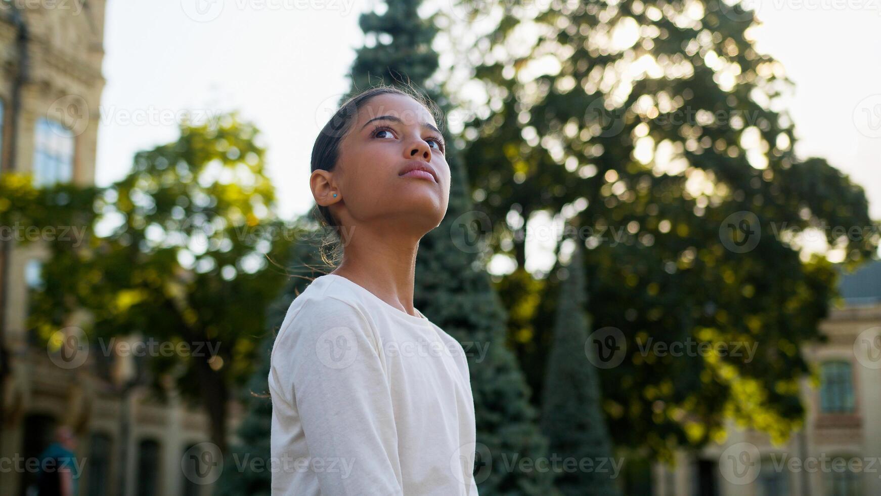 Thoughtful pensive multiethnic girl African American child latino schoolgirl little kid daughter teen student pupil school elementary education looking away outdoors think dream study learn knowledge photo