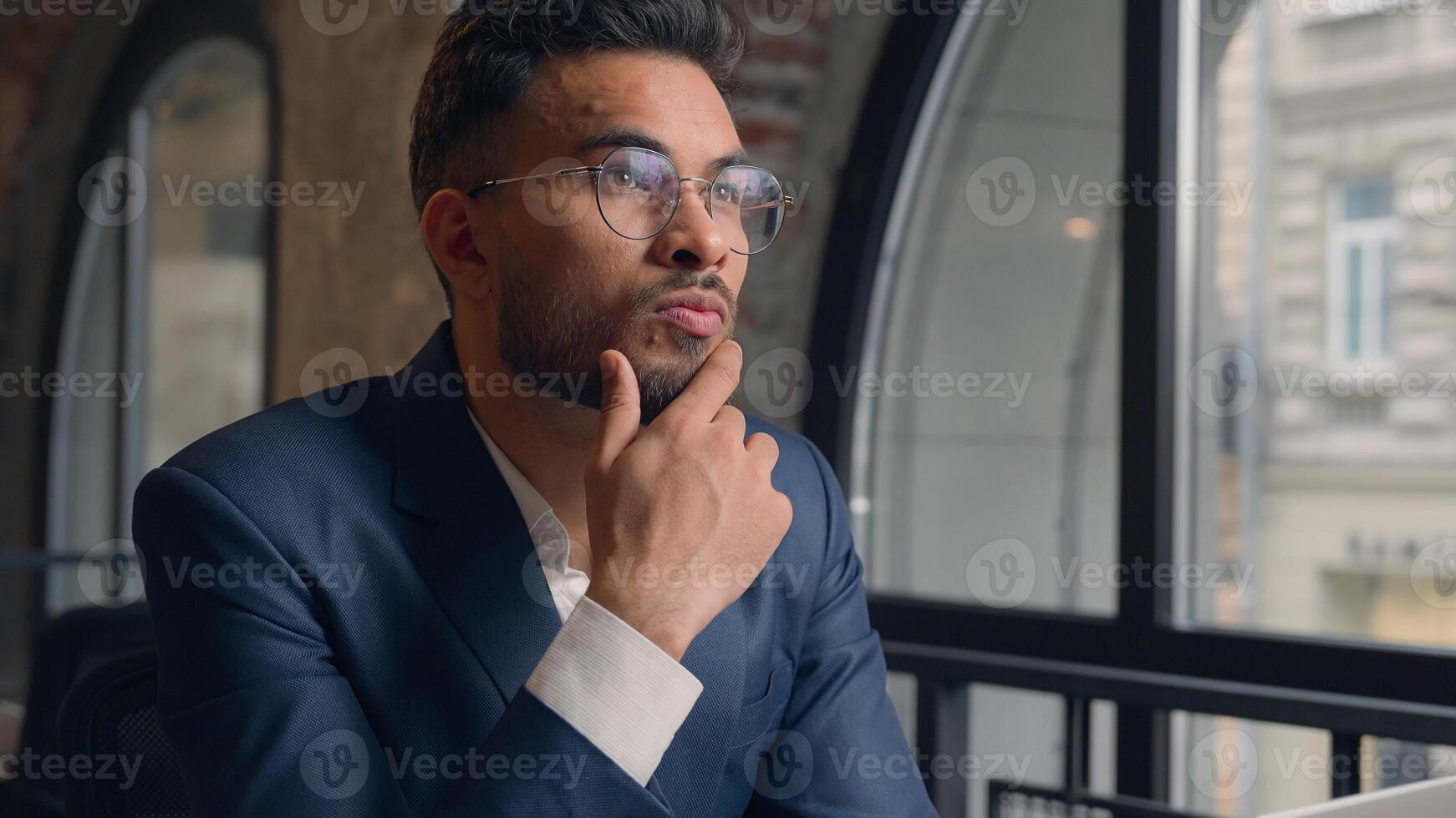 Thoughtful puzzled businessman Arabian Indian man thinking male guy employer worker think idea business plan strategy ponder consider doubt choose remember decide search deep thought question indoors photo
