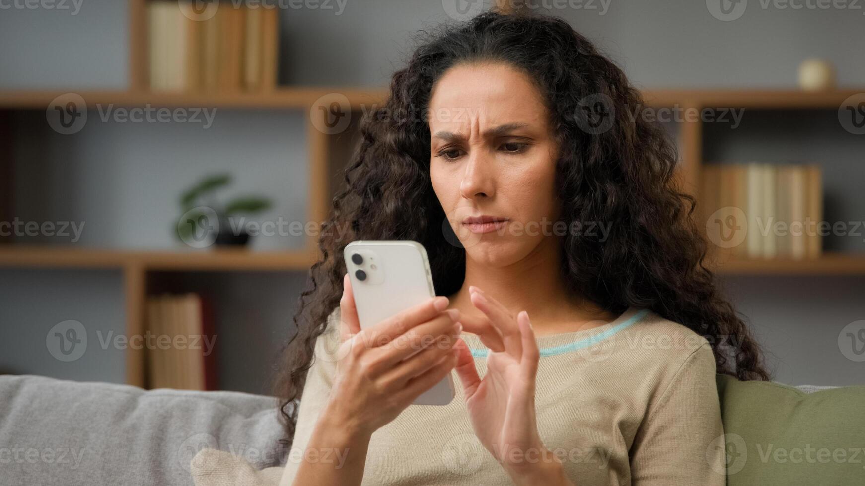 Closeup angry confused puzzled stressed nervous adult woman looking at cellphone screen at home has trouble with wifi connection feeling frustrated of receiving message or email with bad news chatting photo