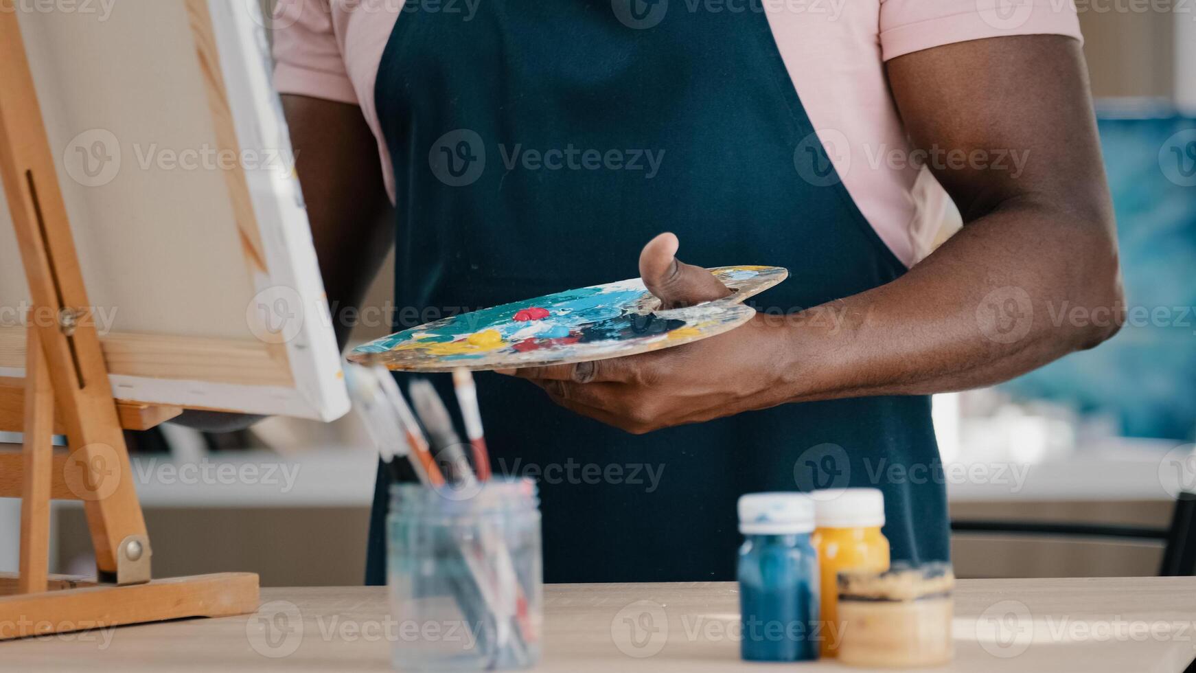 Middle-aged mature senior 50s African artist painter painting drawing picture in art studio with acrylic oil draw on canvas makes mistake upset feels dissatisfied using wrong paint emotional reaction photo
