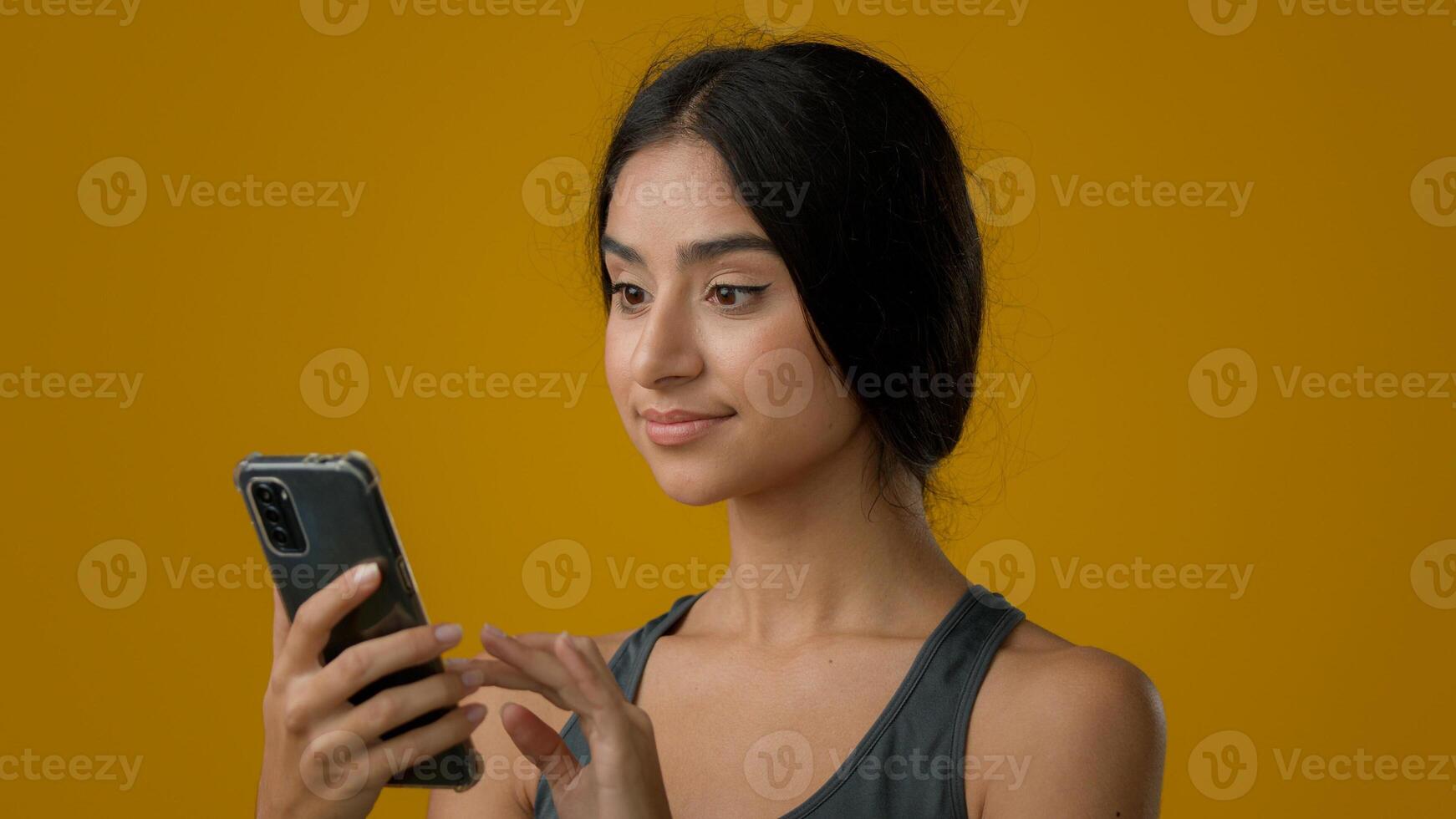 Close up Indian ethnic woman girl lady female smile browsing cell smartphone looking at camera with recommendation gesture swipe in mobile phone showing thumb up approve online bet winning super app photo