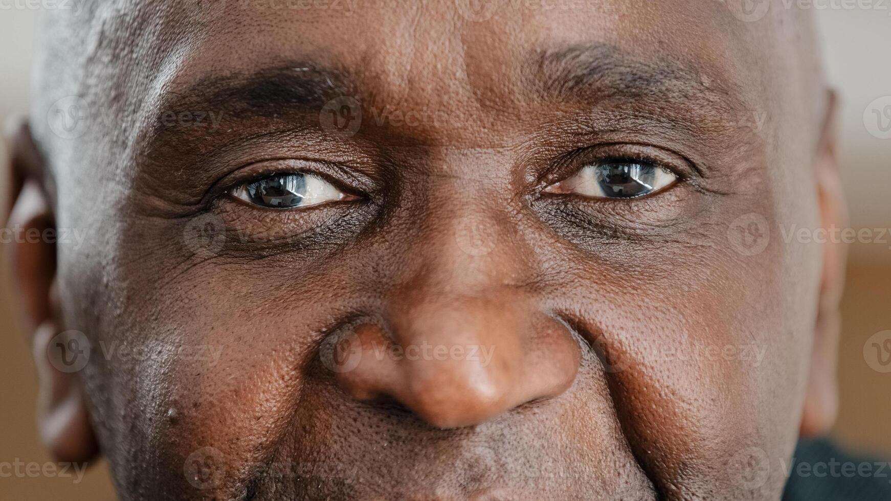 Close up part male face happy elderly African American man smiling with friendly dark black eyes. Handsome mature senior citizen with wrinkles looking blink wink with eye friendly eyesight good vision photo