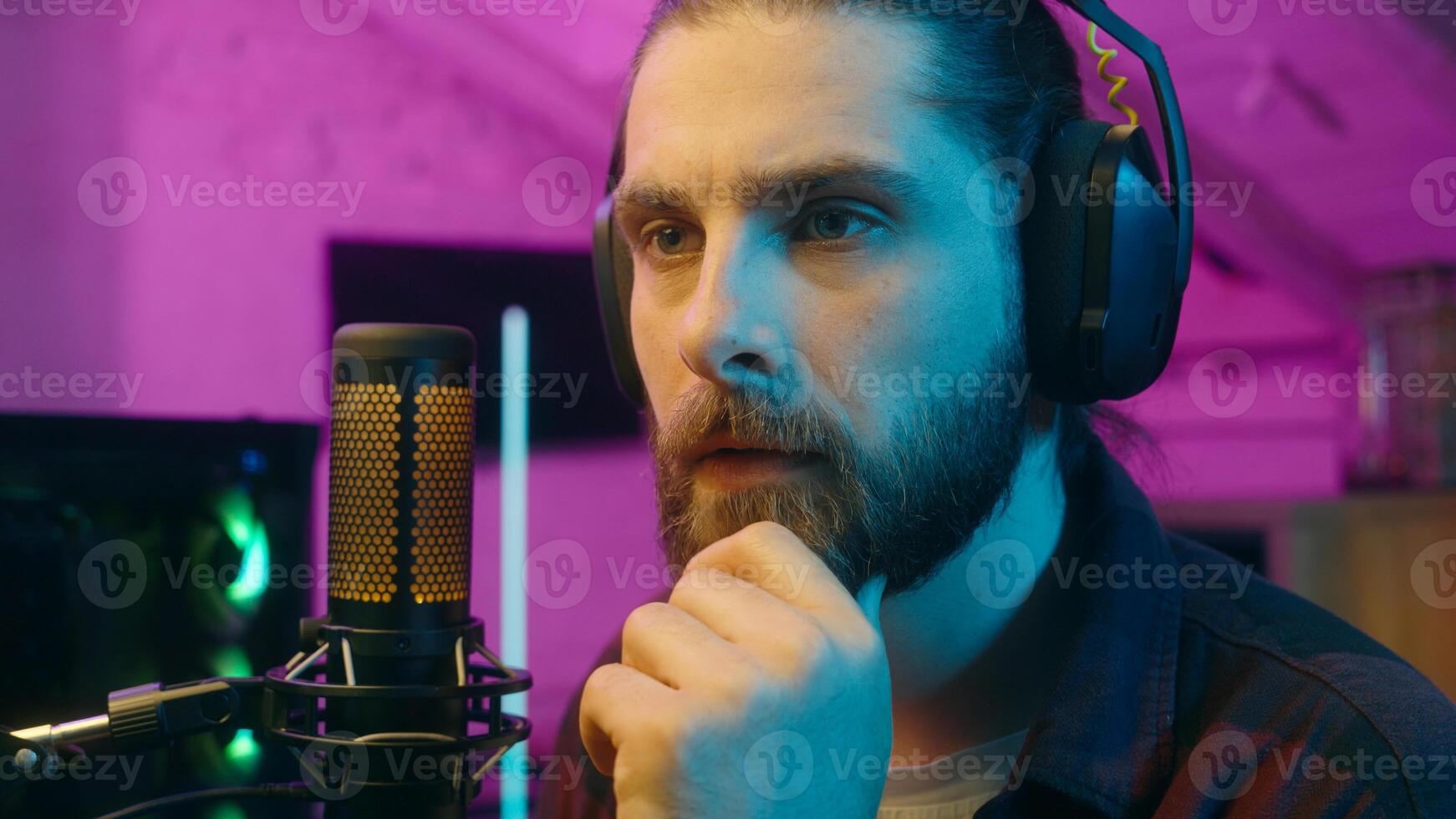 Puzzled thoughtful Caucasian influencer guy blogger player streamer man vlog contemplating cyber sport neon thinking gaming decision at home addict male gamer host play computer game blog idea thought photo