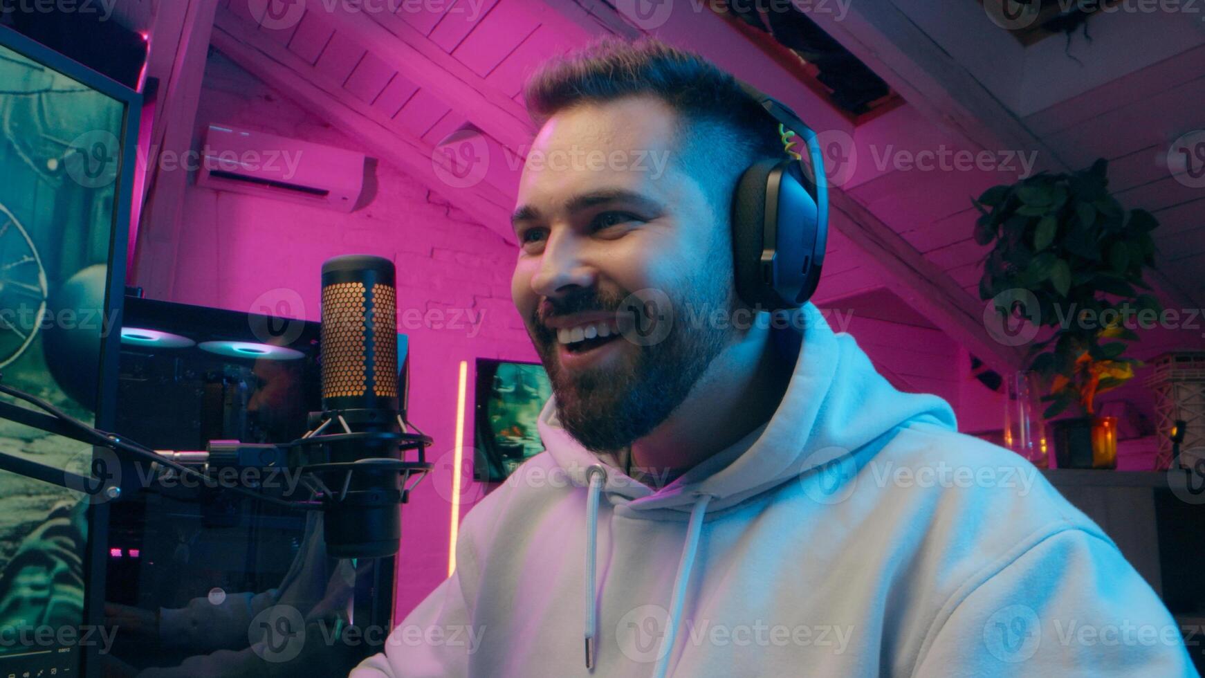 Happy Caucasian male gamer blogger vlog close up talking microphone playing computer gadget game at home e-sport neon guy influencer speak mic host man streaming streamer smile radio gaming vlog photo