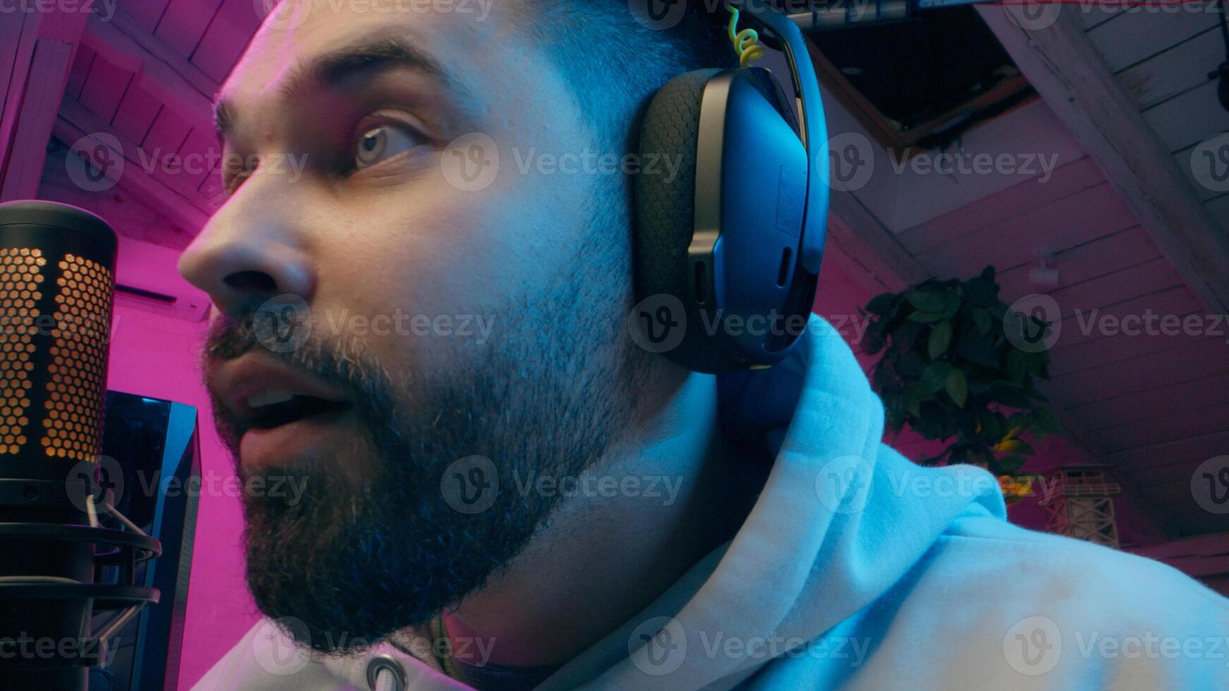 Happy Caucasian male gamer blogger vlog close up talking microphone playing computer gadget game at home e-sport neon guy influencer speak mic host man streaming streamer smile radio gaming vlog photo